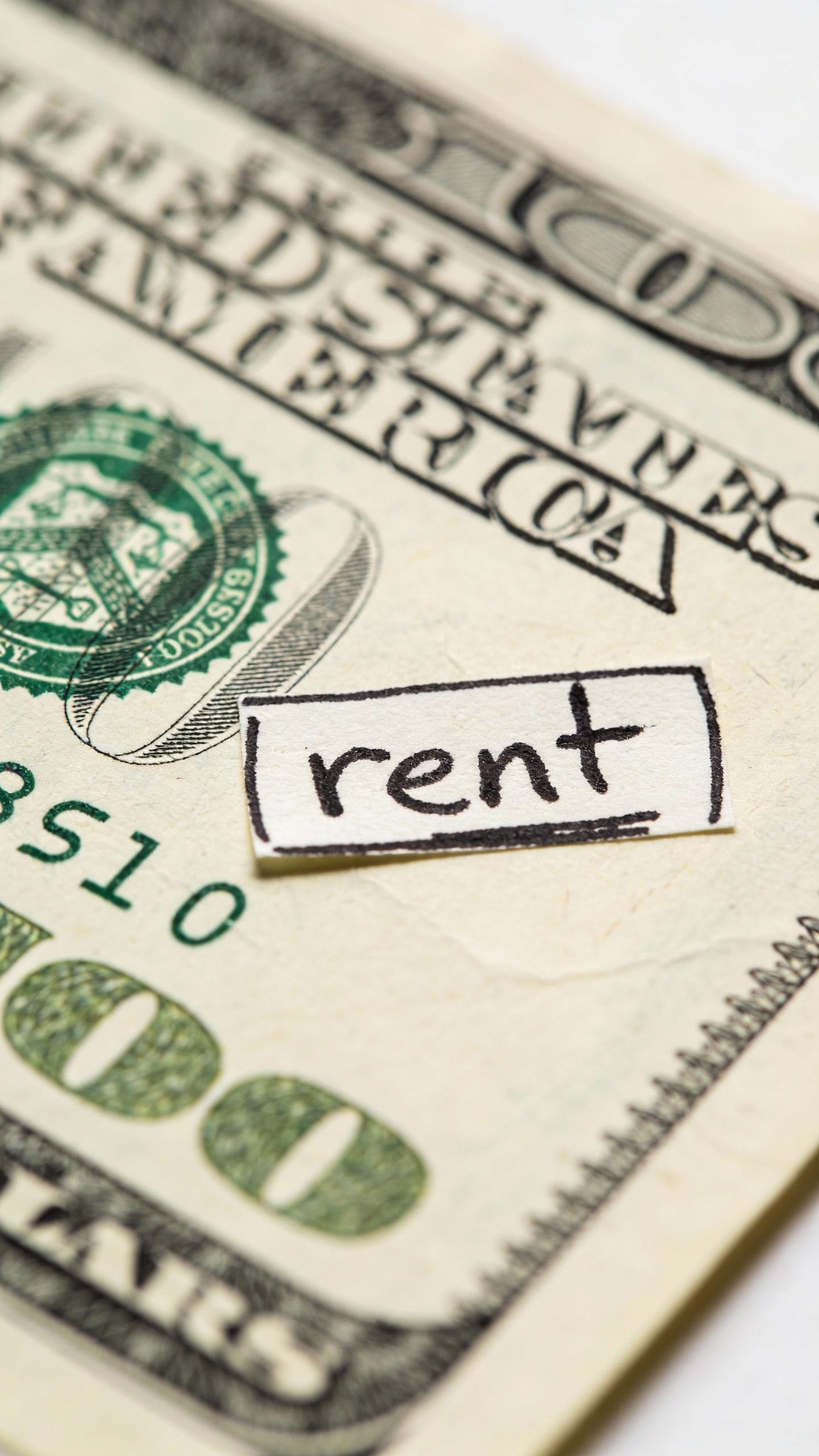 closeup of a single dollar bill labeled “rent” with marker