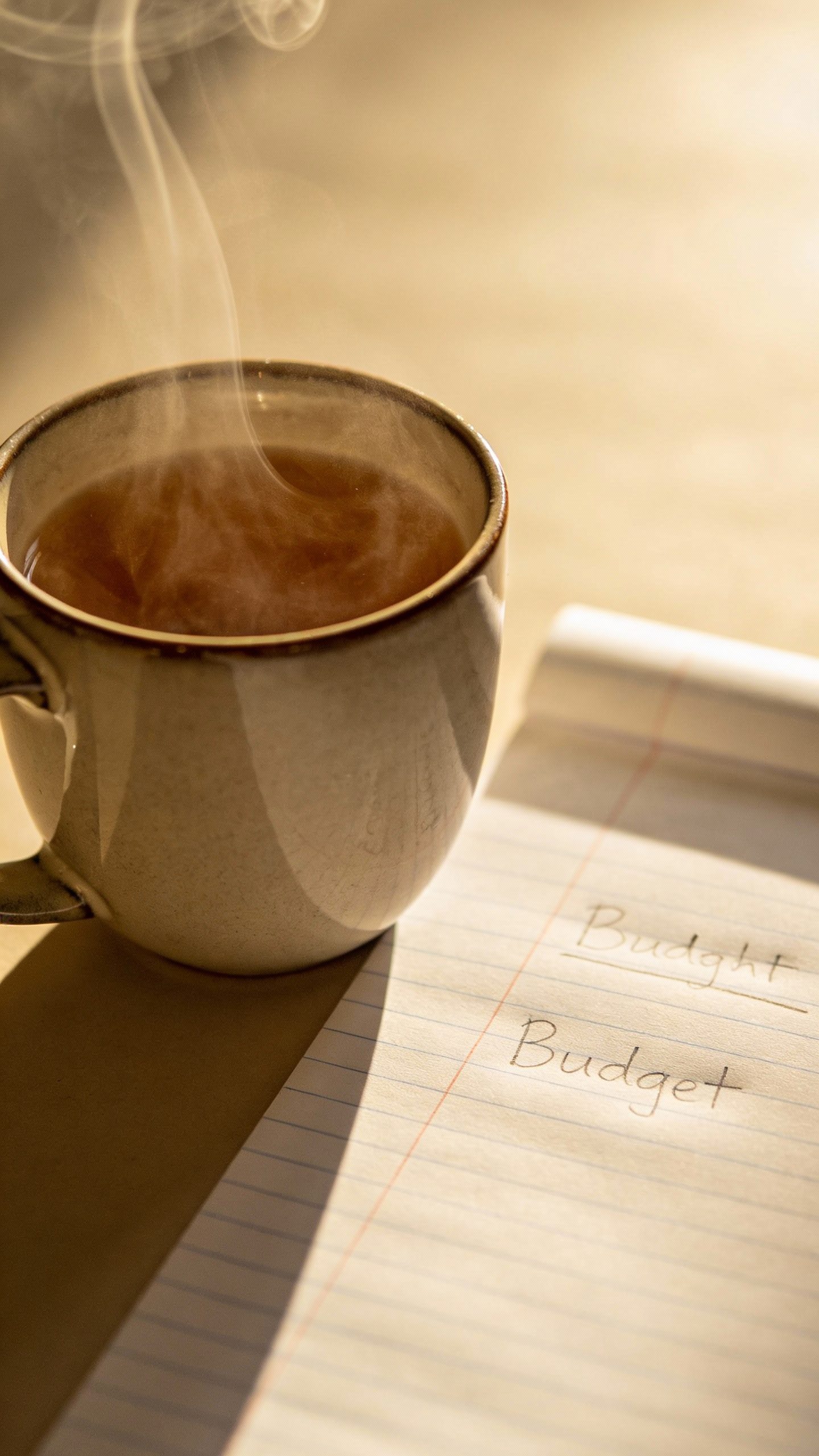 steaming mug of tea beside simple budget sheet
