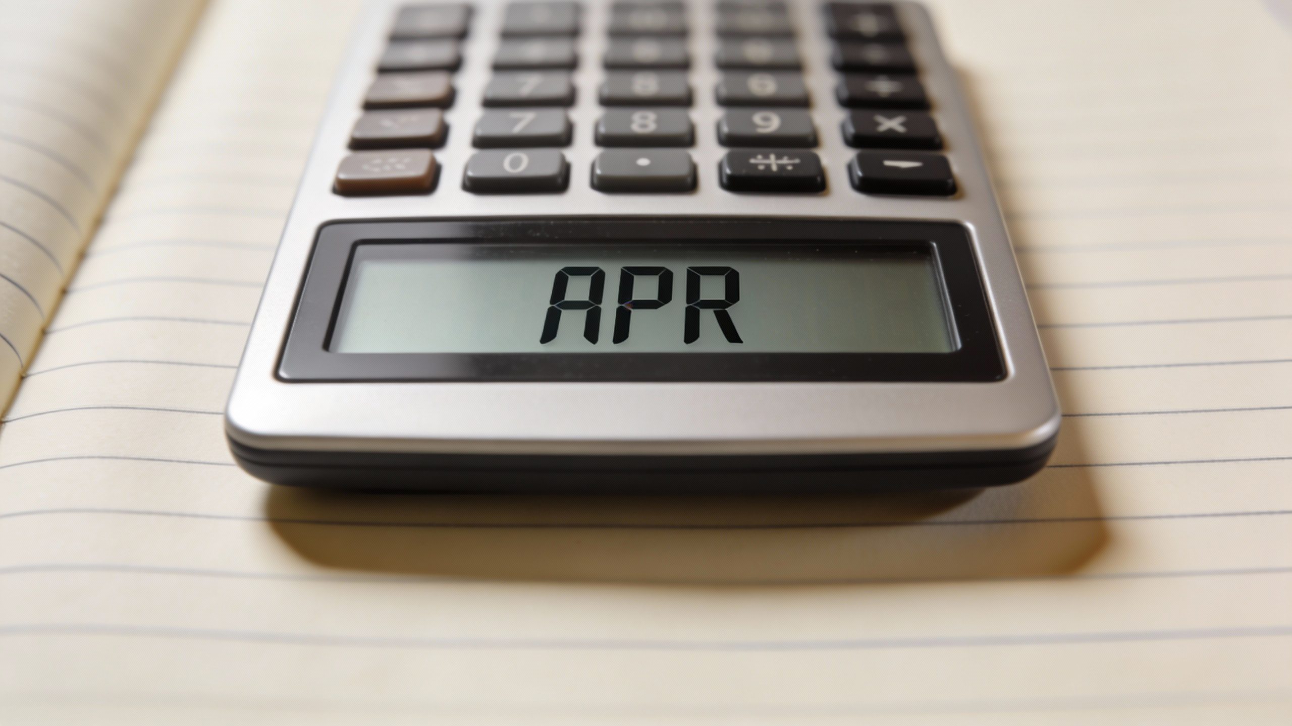 closeup of calculator displaying APR on lined notebook
