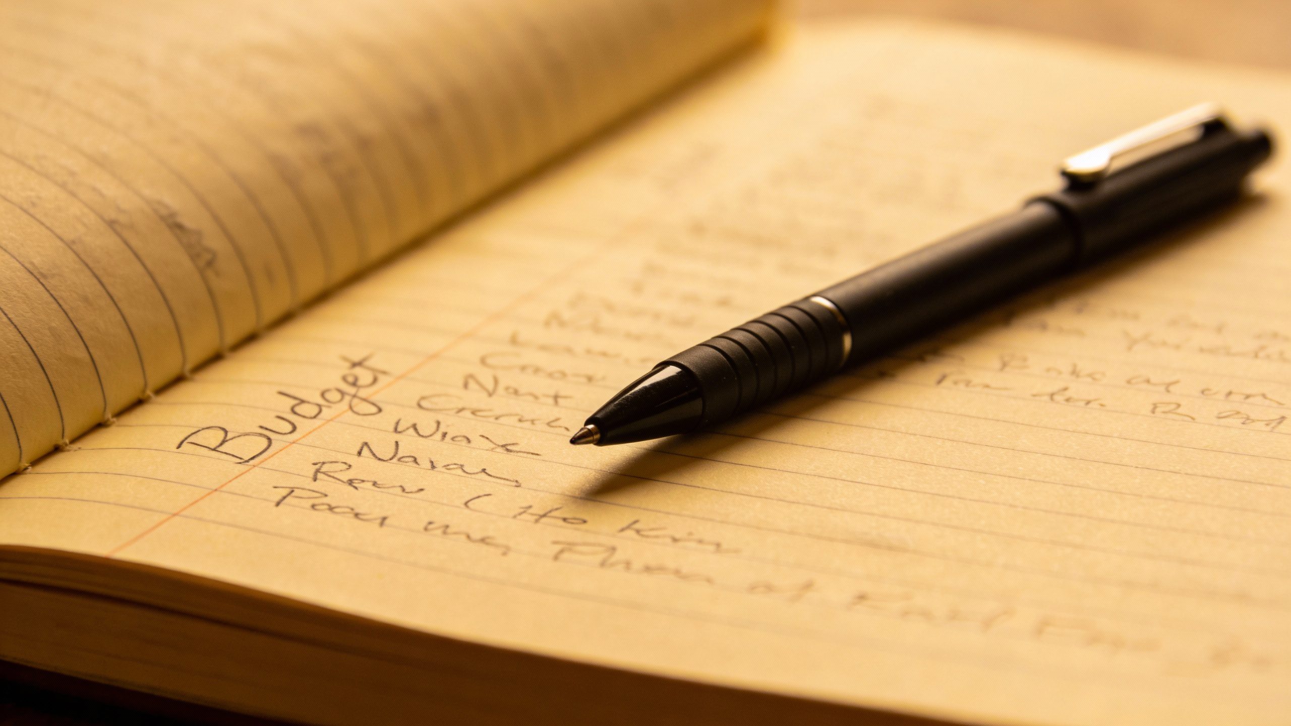 **Closeup of a handwritten budget notebook with pen**