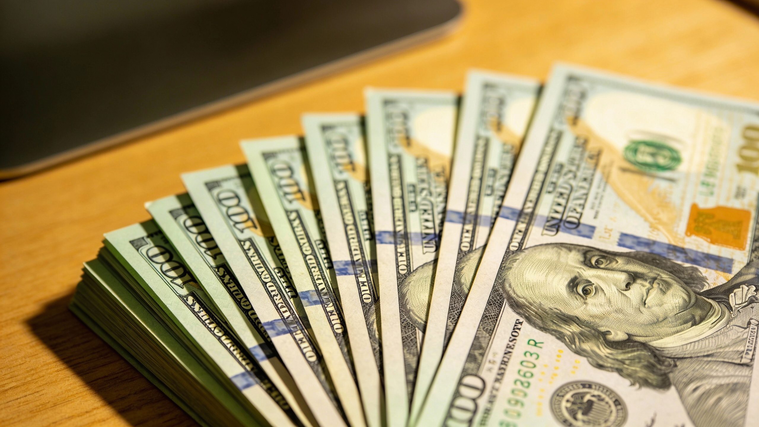closeup of $1,000 in crisp $100 bills, on desk