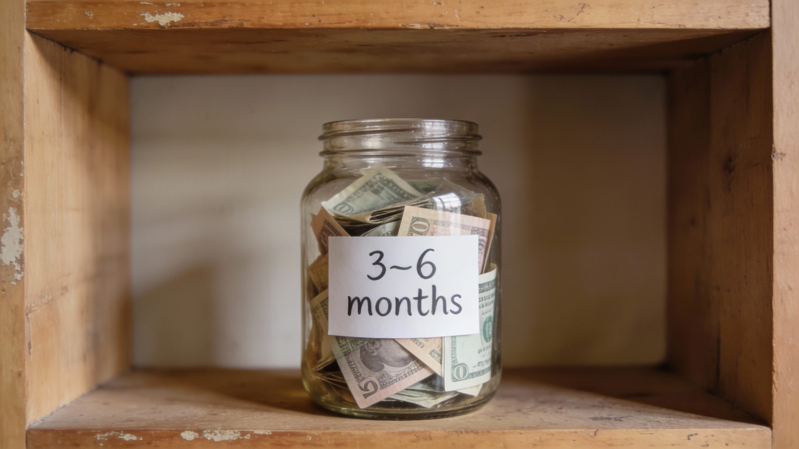 emergency fund glass jar labeled “3–6 months” on shelf