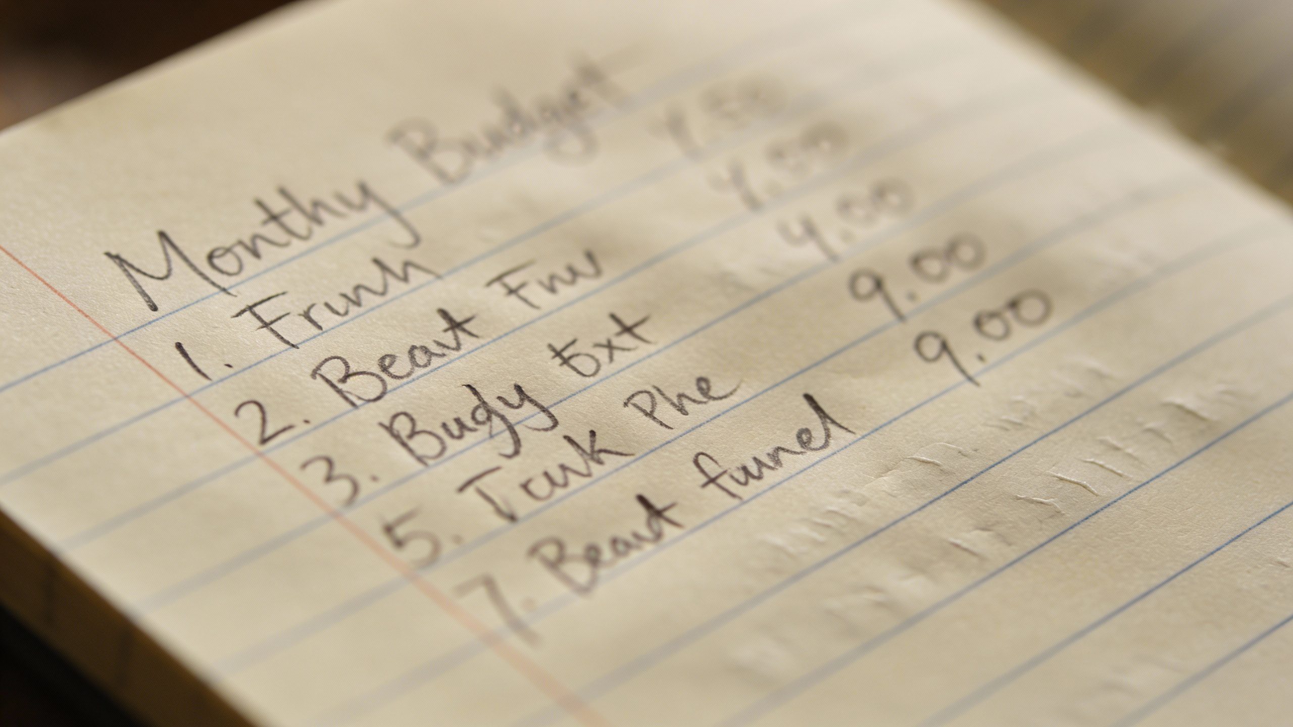 closeup of handwritten monthly budget on lined notebook