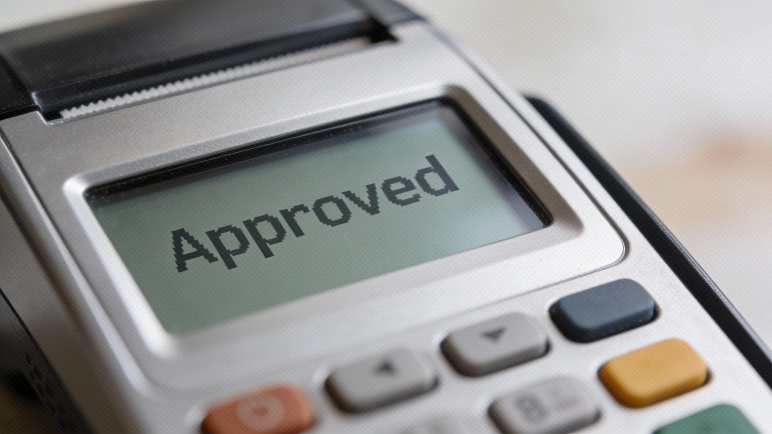 Closeup of a debit card tapping terminal with “Approved” display