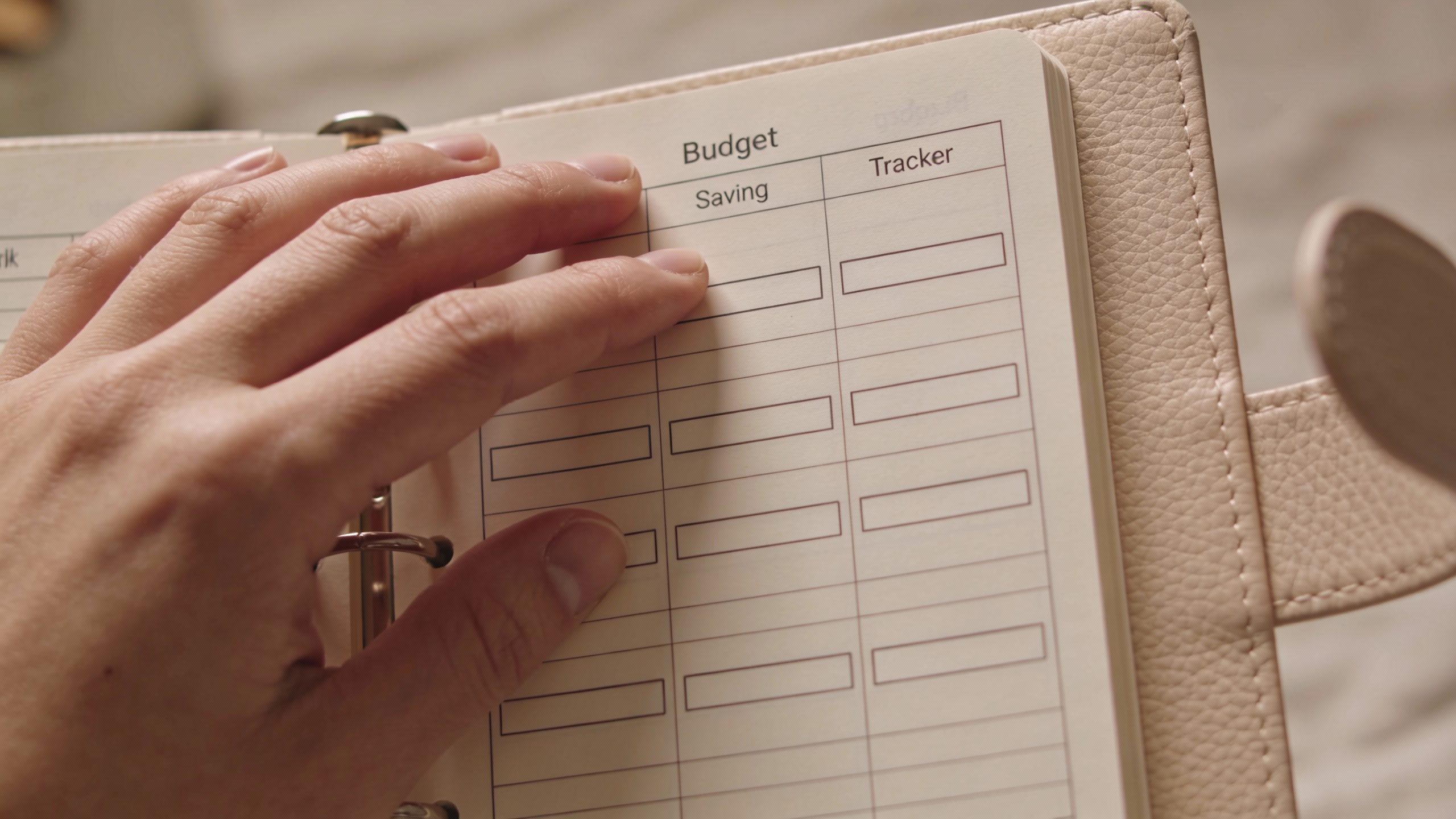 **Hand holding a budget planner open to a savings tracker page**