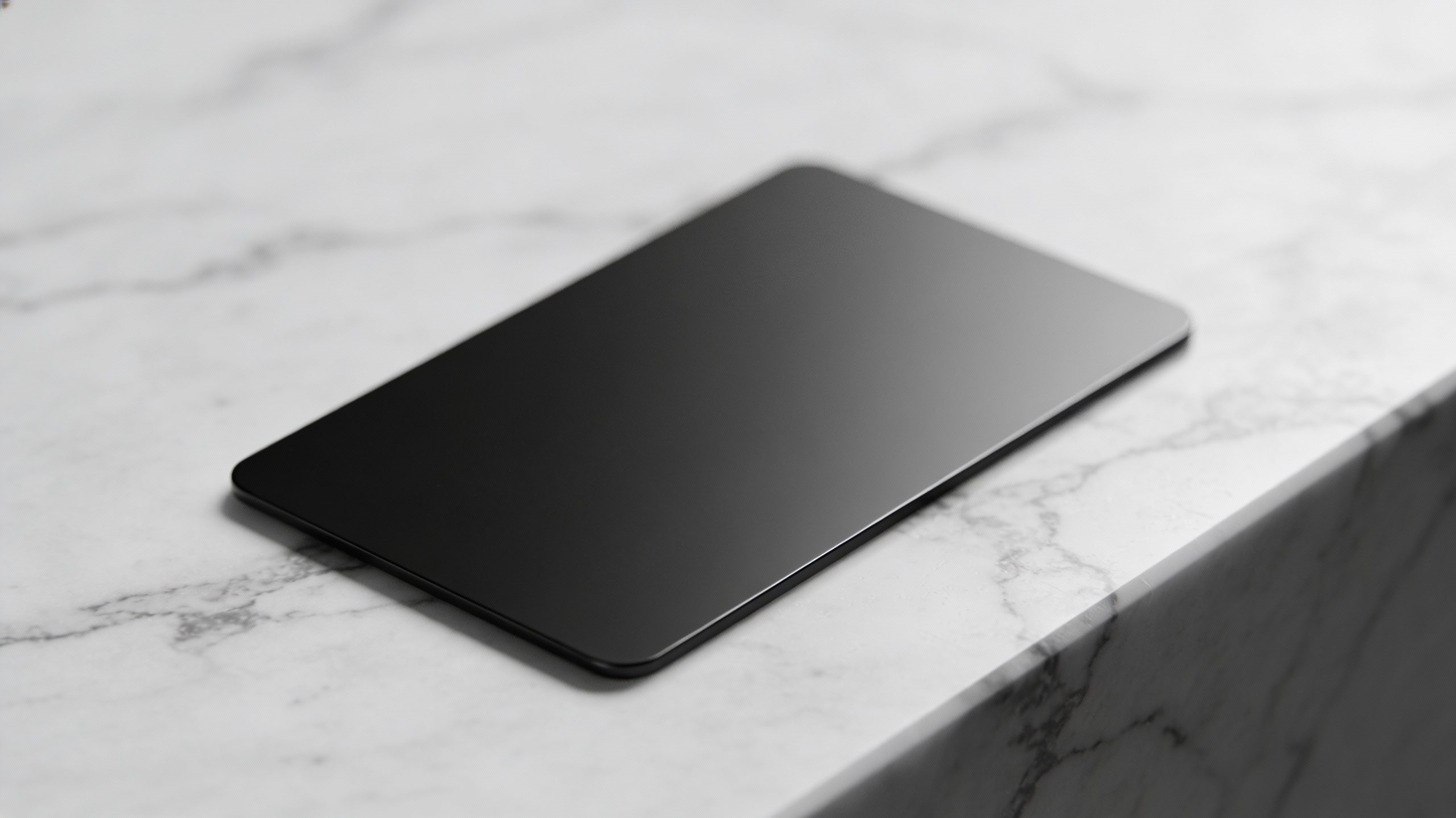 **Single sleek black credit card on a marble surface**