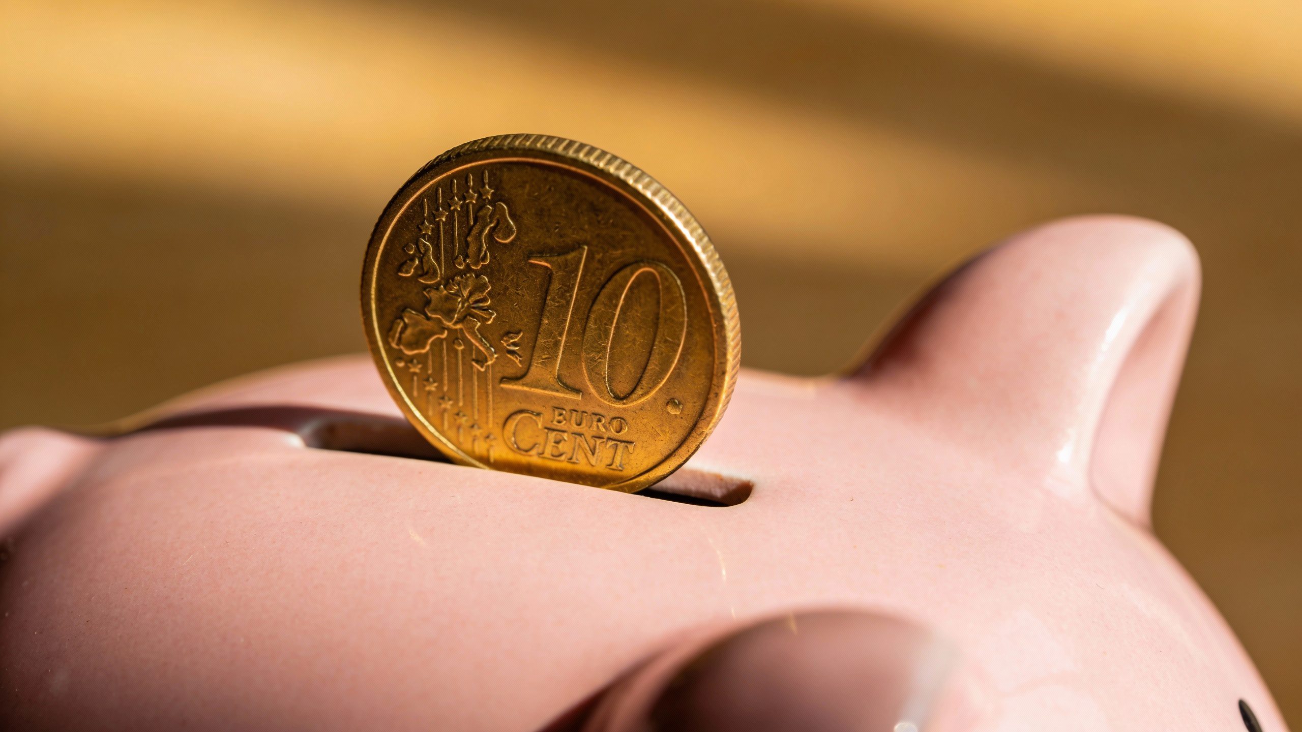 **Gold coin balanced on the edge of a piggy bank**