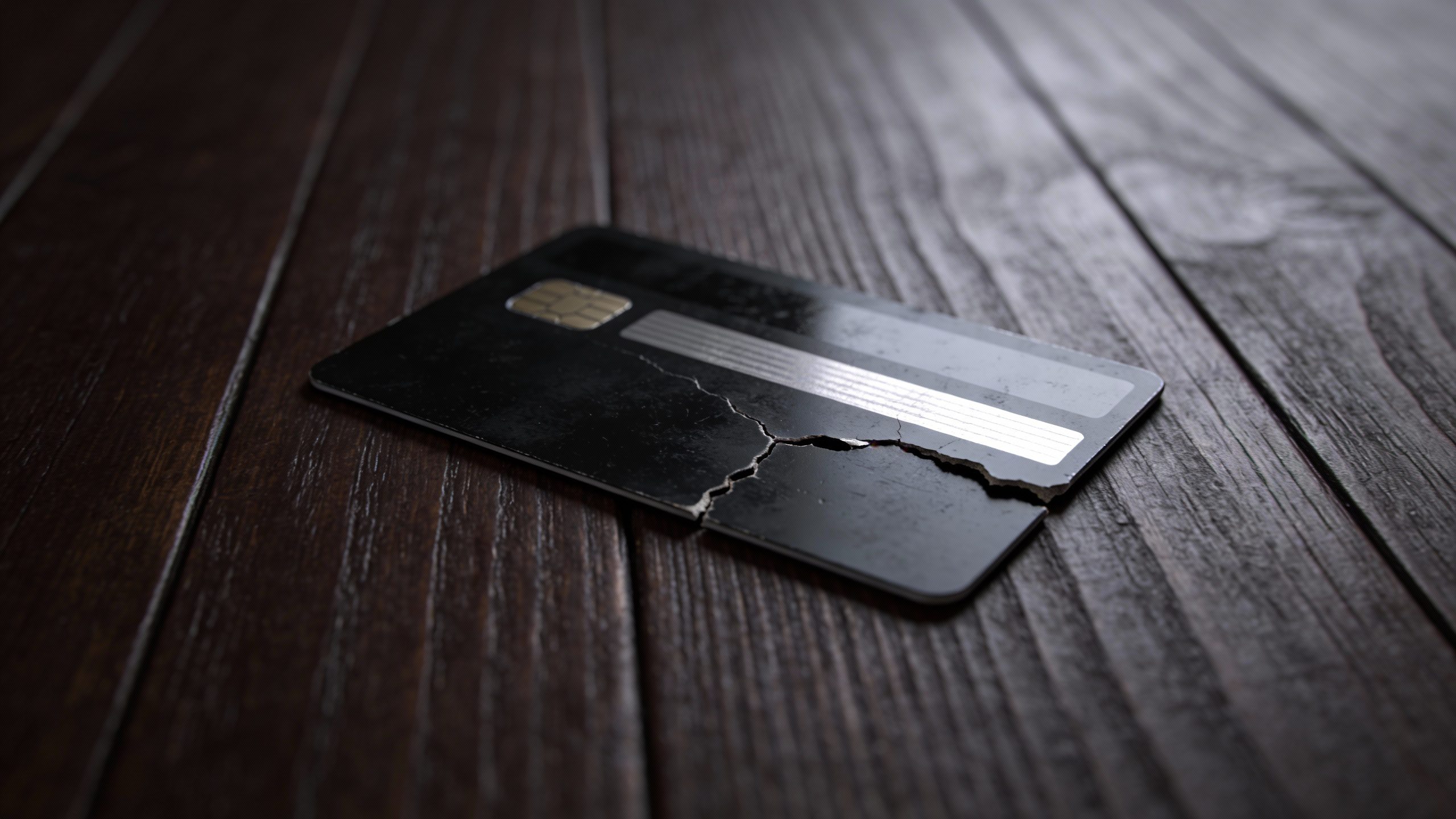 **Single torn credit card on a dark wooden table**