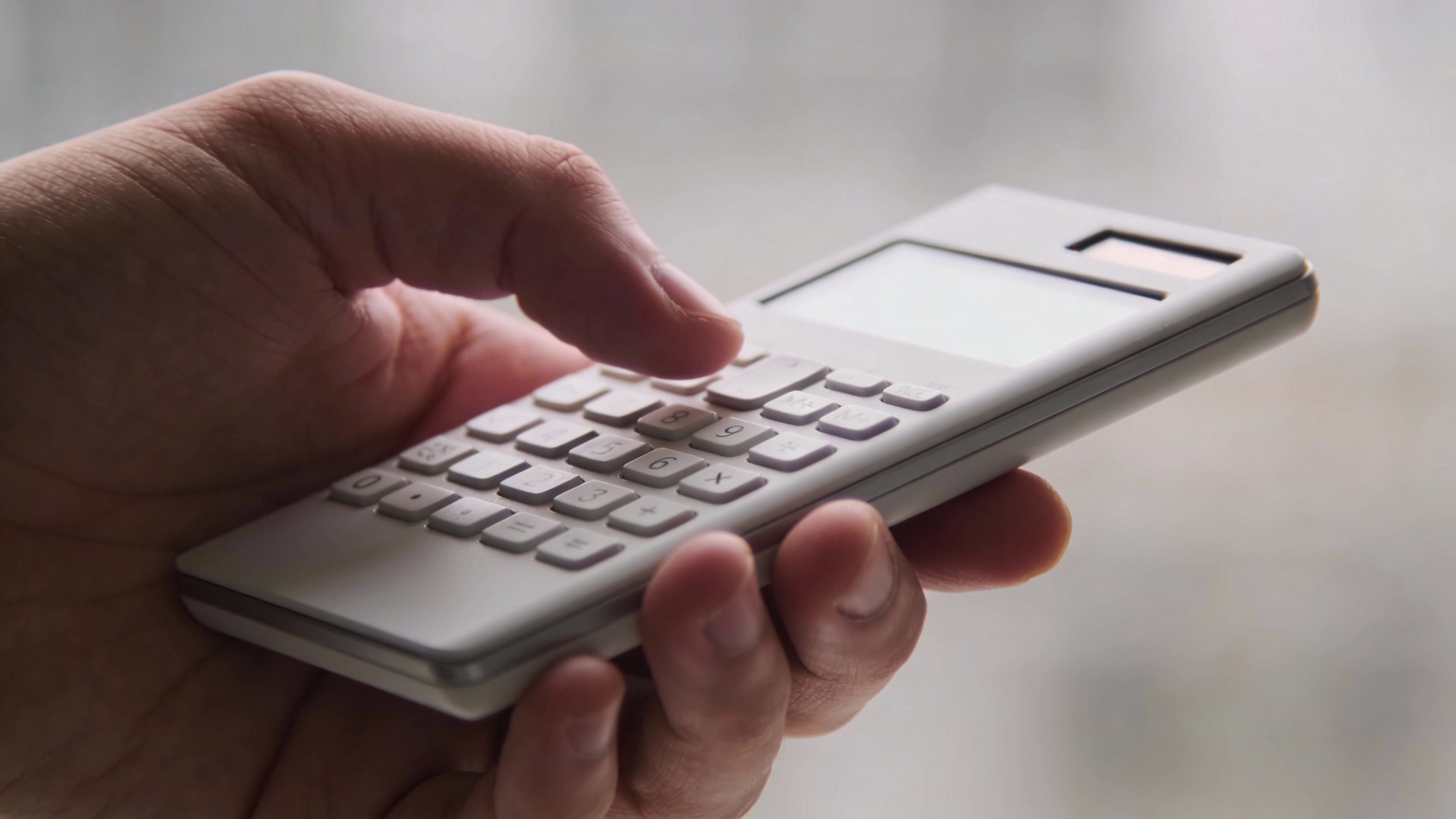 **Hand holding a calculator with a blank screen**