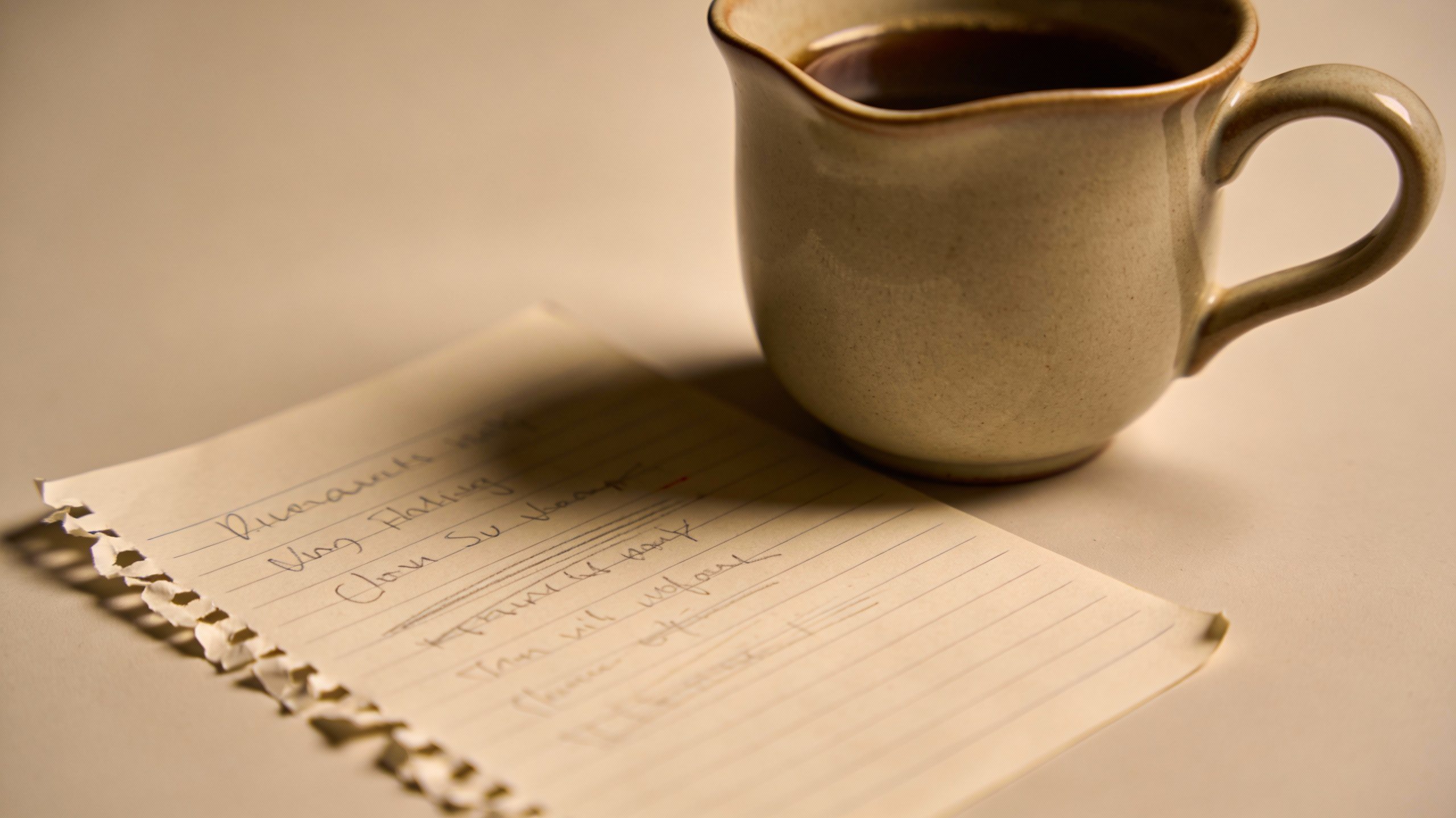**Single coffee cup next to handwritten budget notepad**