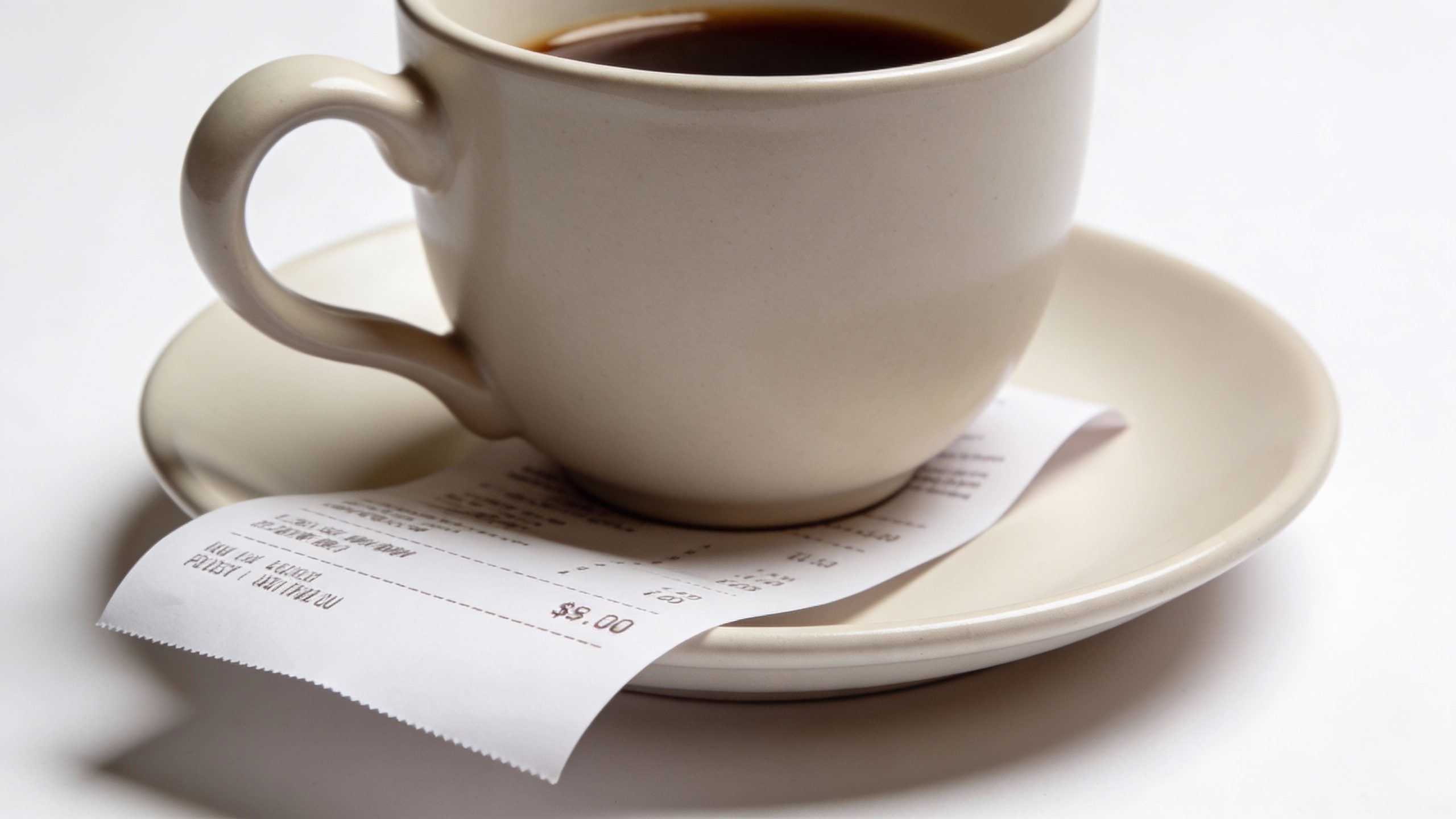 **Isolated coffee cup with receipt tucked under the saucer**