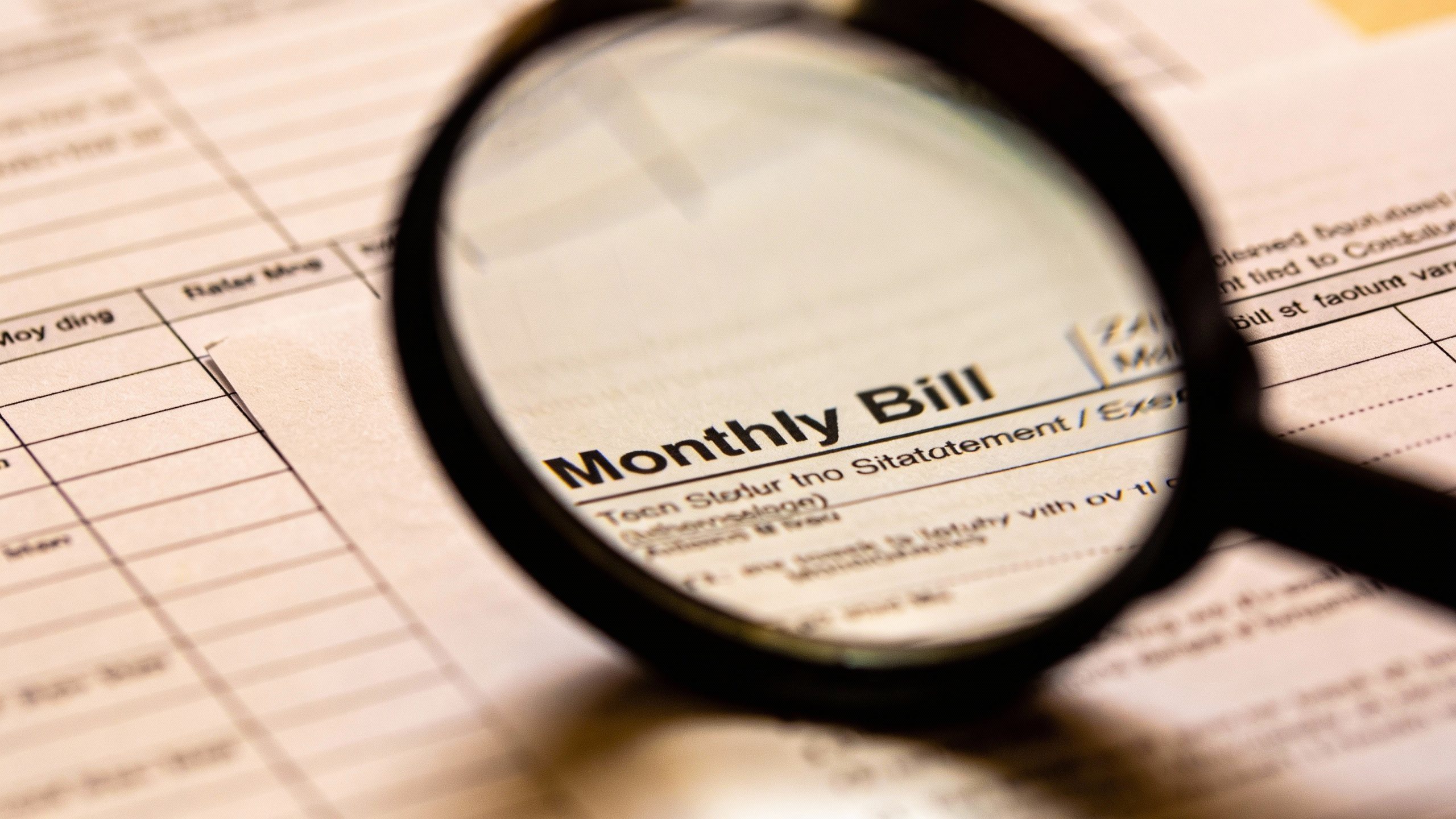 Closeup of a magnifying glass over a monthly bill statement