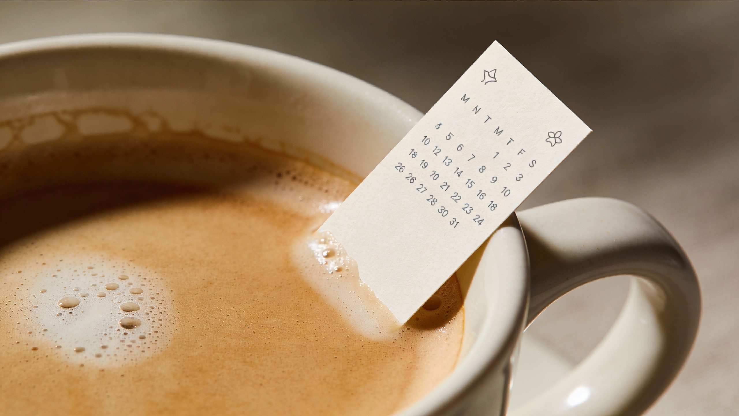 Closeup of a solitary latte cup with a small calendar showing micro-milestones page edge