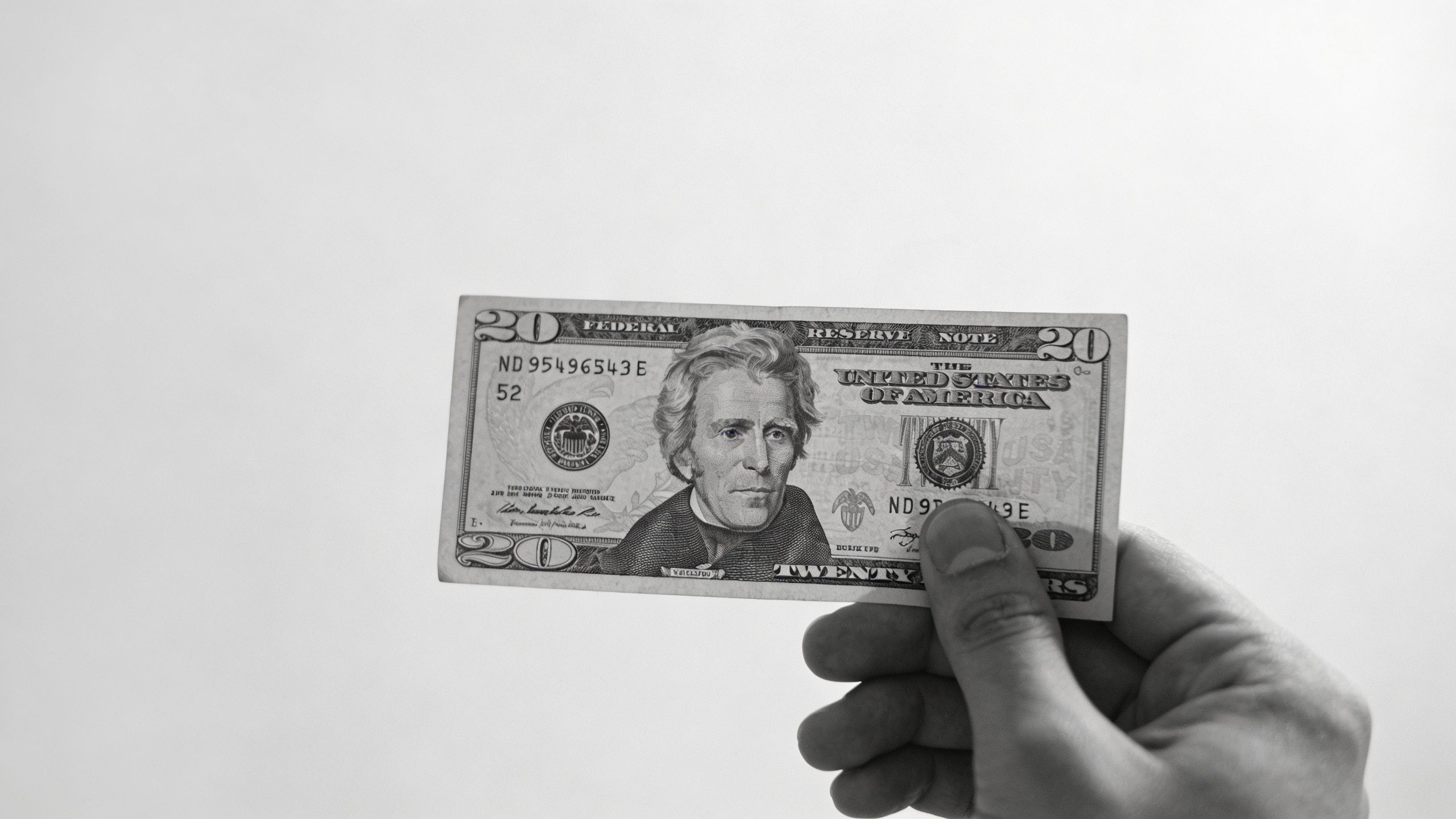 **Hand holding a $52 bill against a minimalist background**