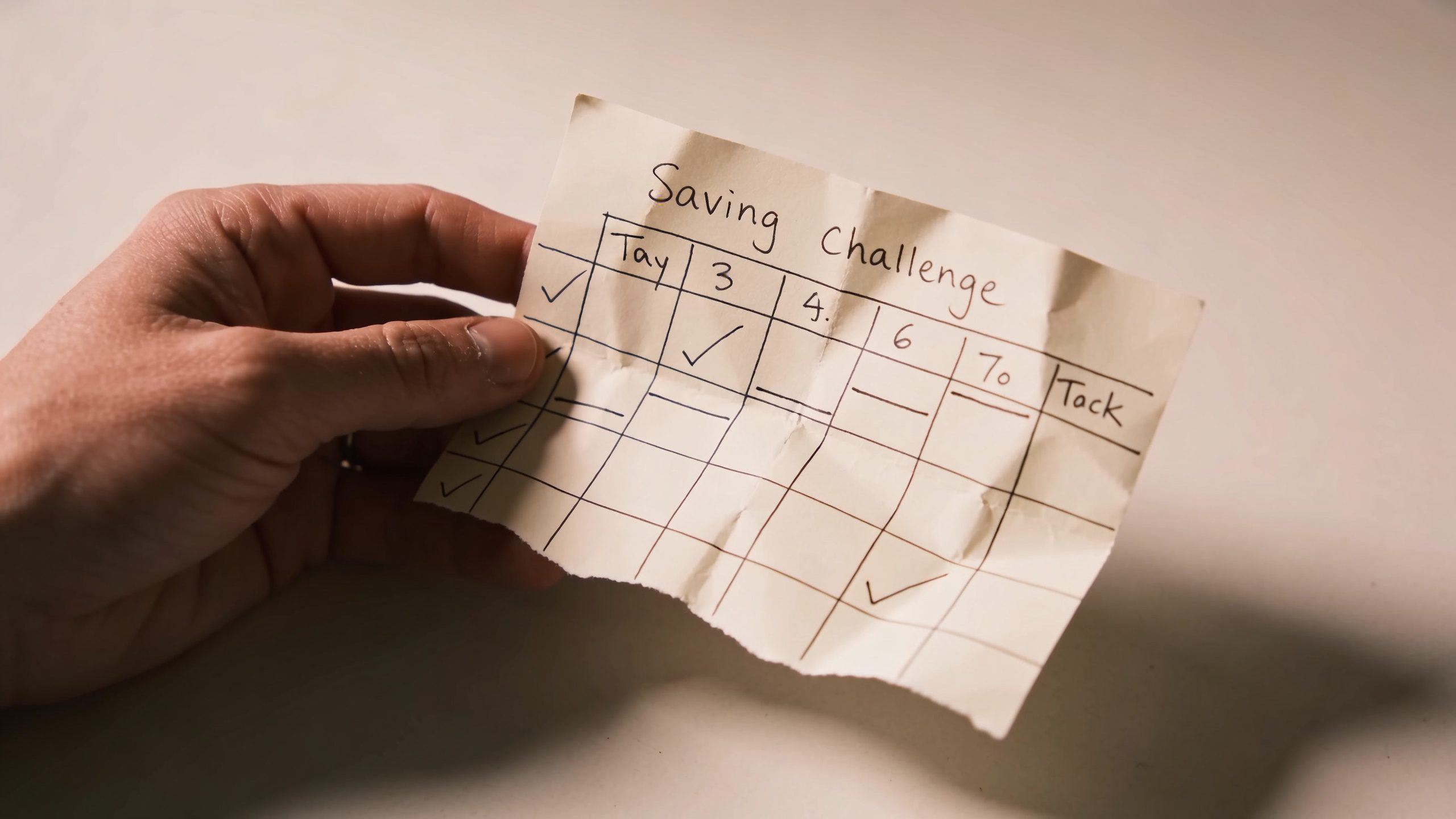 **Hand holding a handwritten savings challenge tracker**