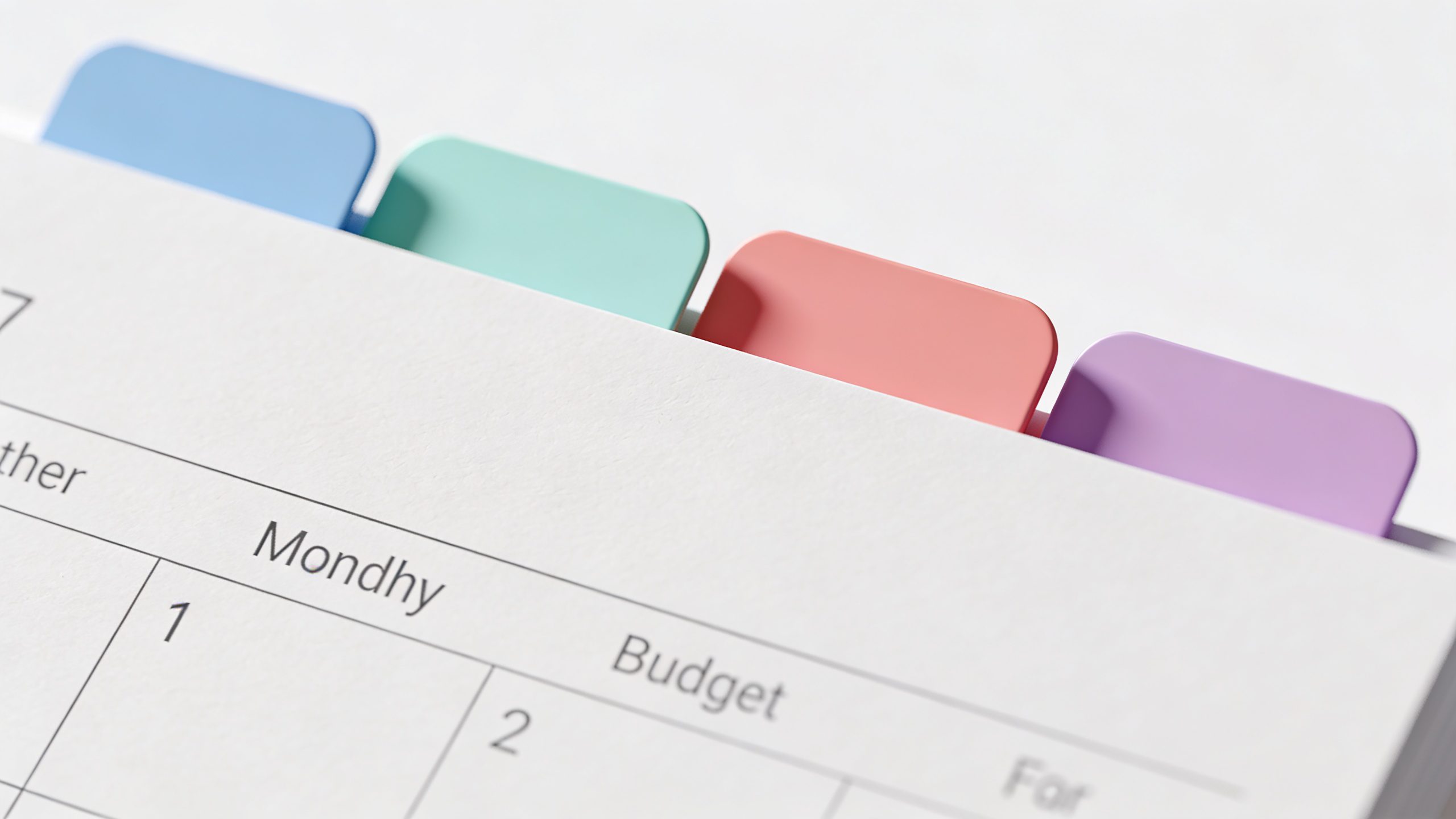 Closeup of a minimalist monthly budget page with colored category tabs
