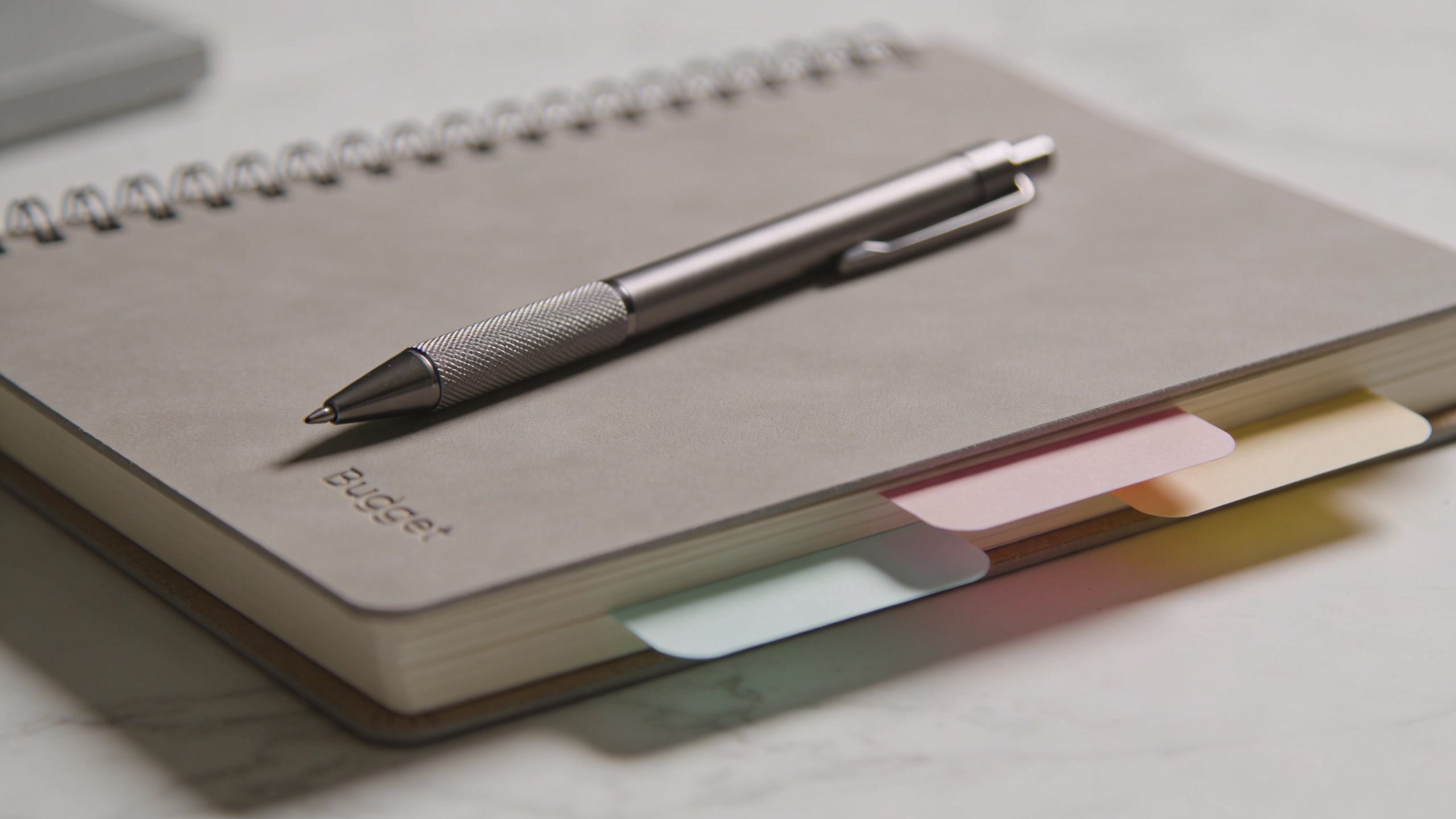 Closeup of a sleek budget planner notebook with a pen and sticky notes