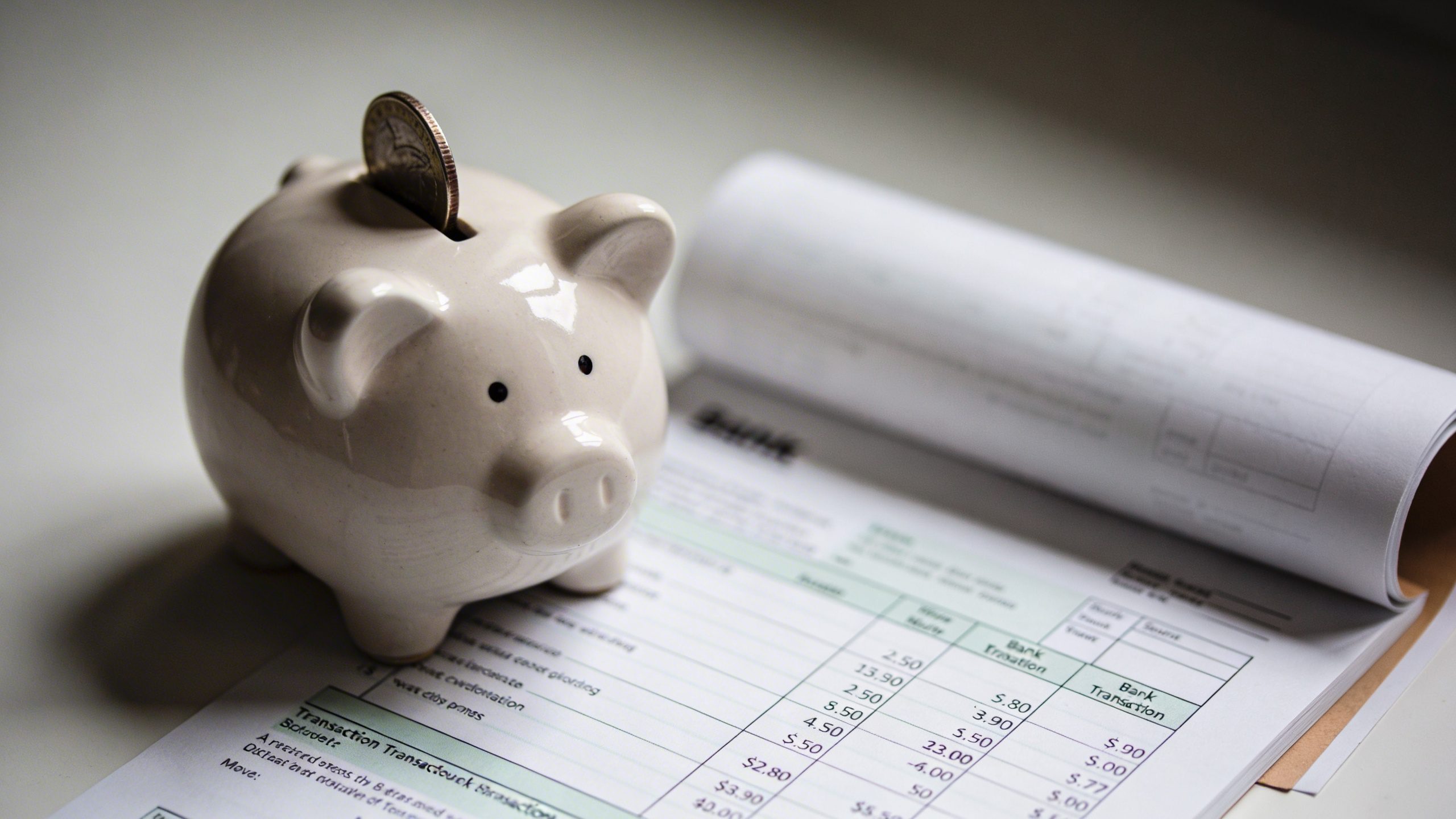 Closeup of a single piggy bank beside a realistic bank statement
