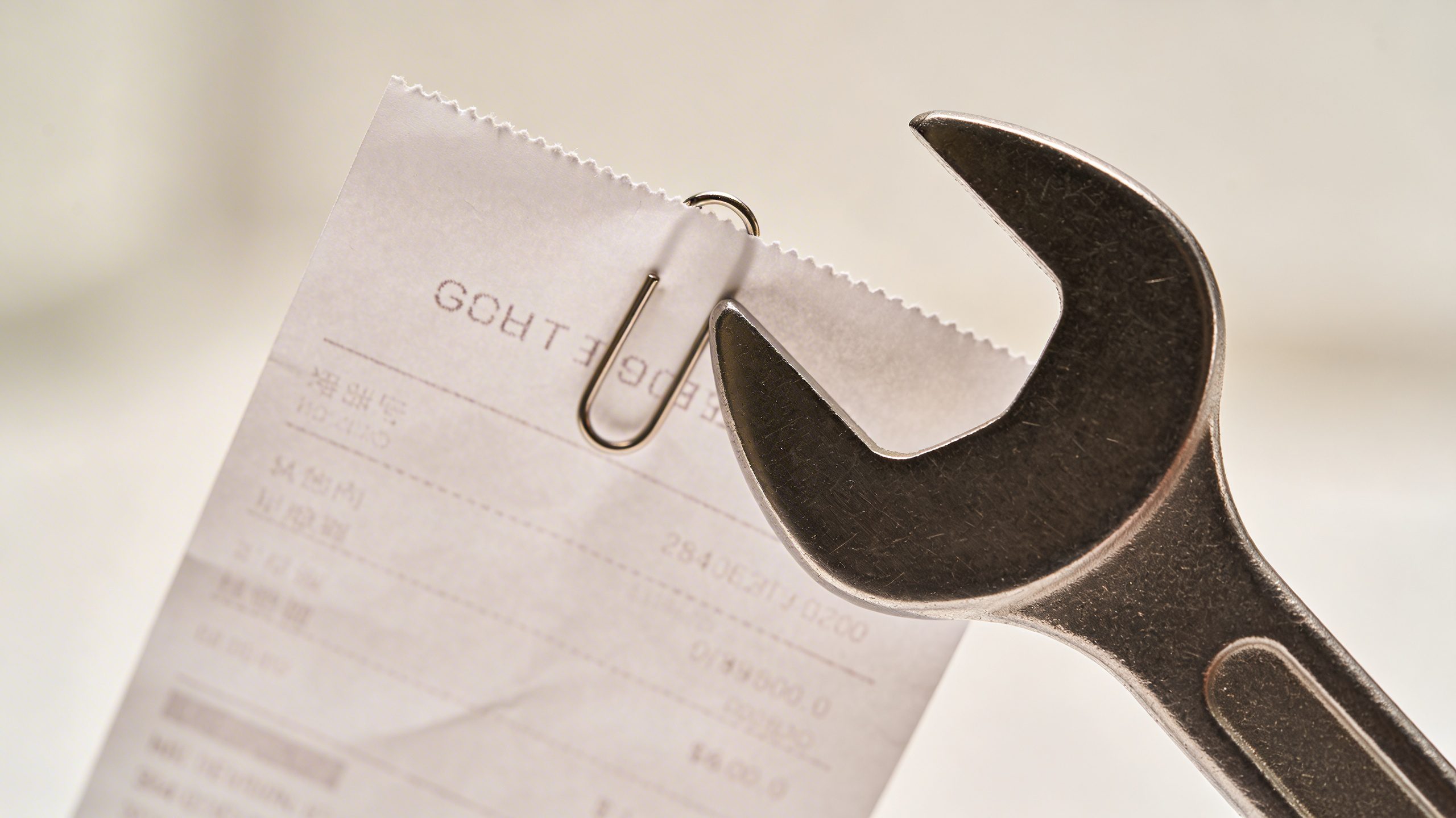 Closeup of a receipt being clipped with a wrench-shaped budget tag in focus