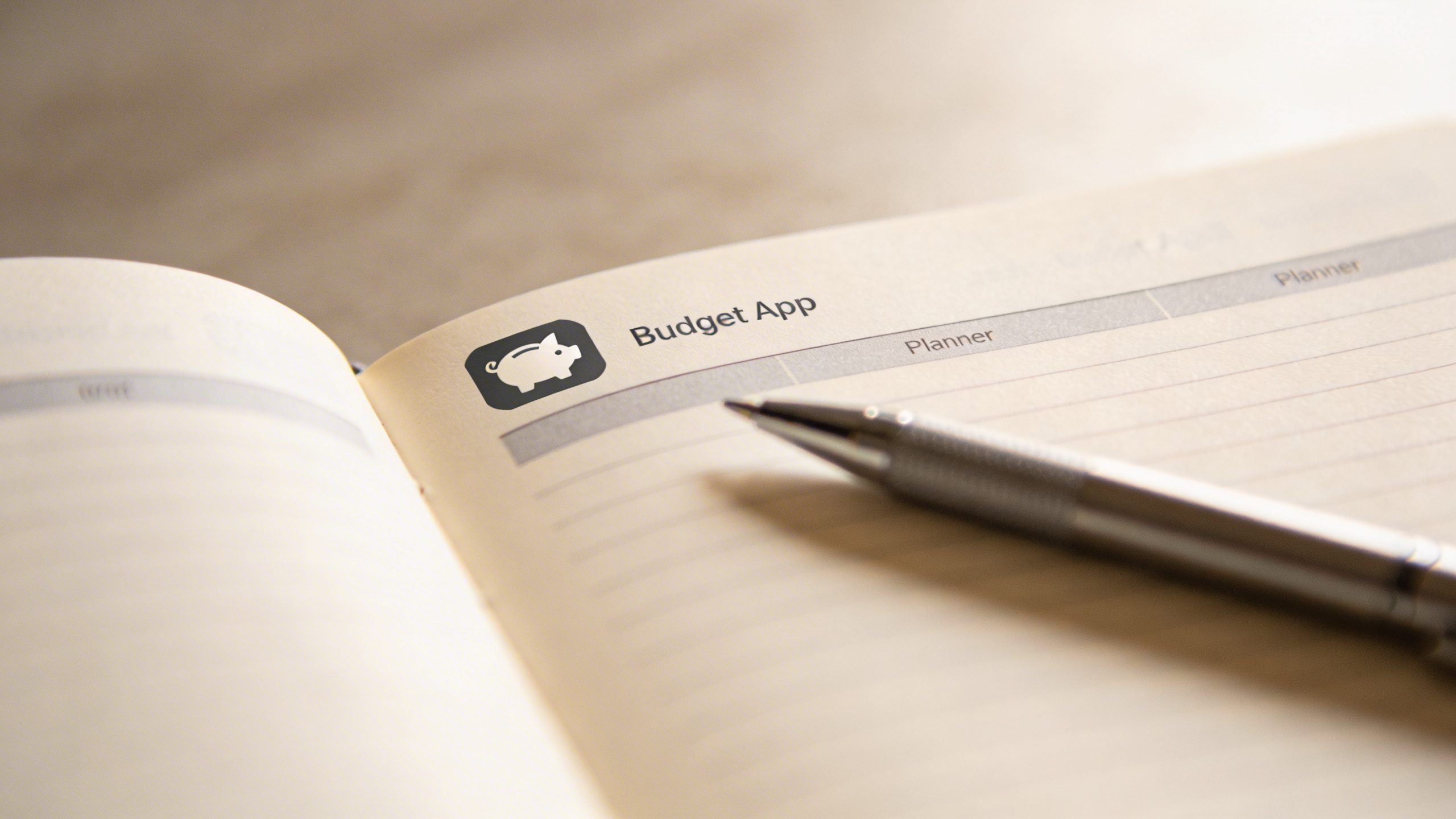 Closeup of a planner and a single pen with a budget app icon on the page header