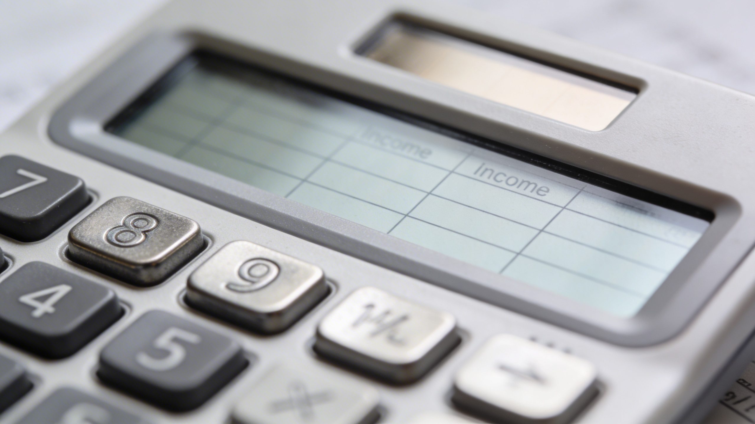 closeup of a calculator with labeled income/expenses sheets