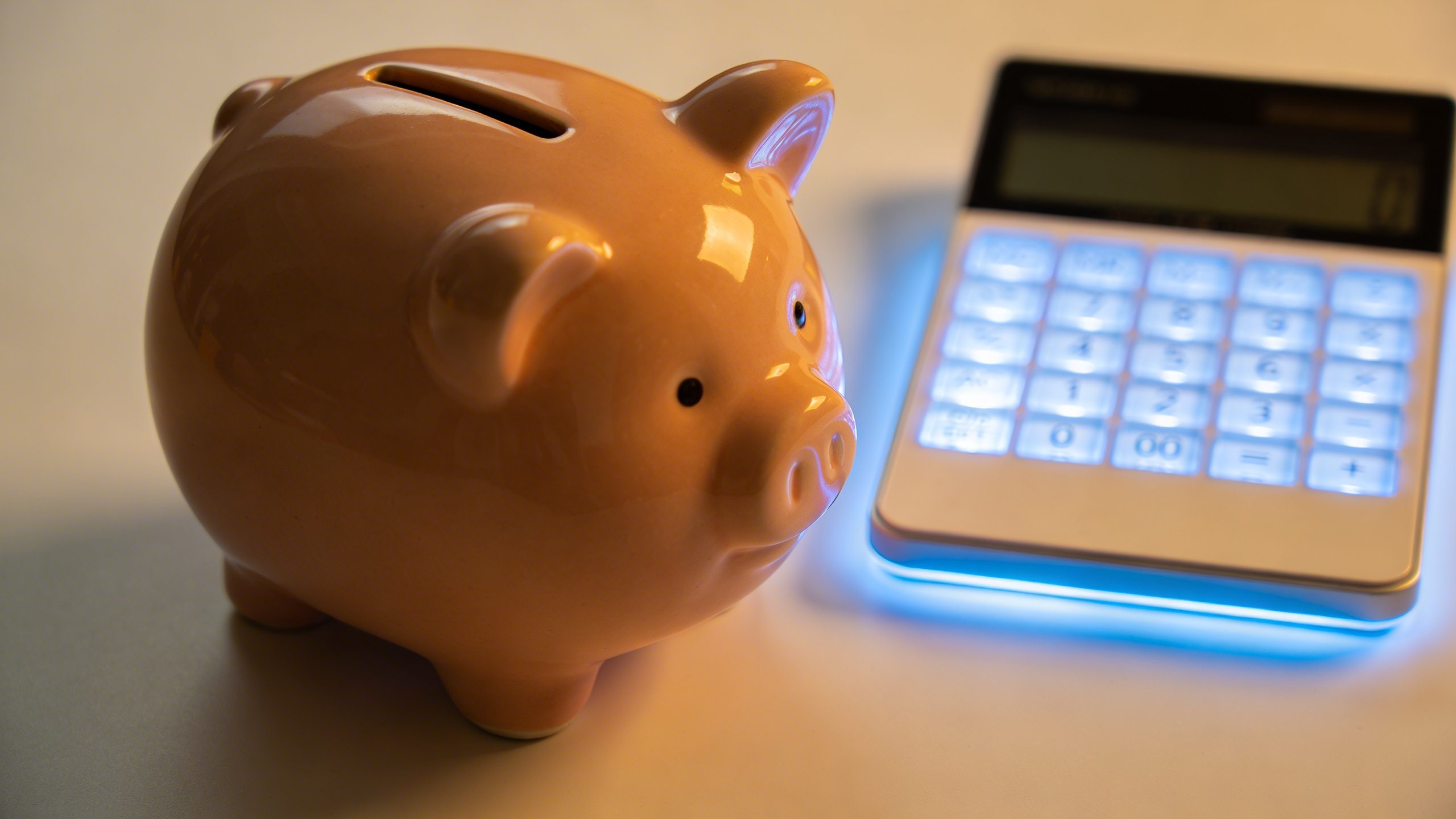 Focused shot of a single piggy bank and calculator glow