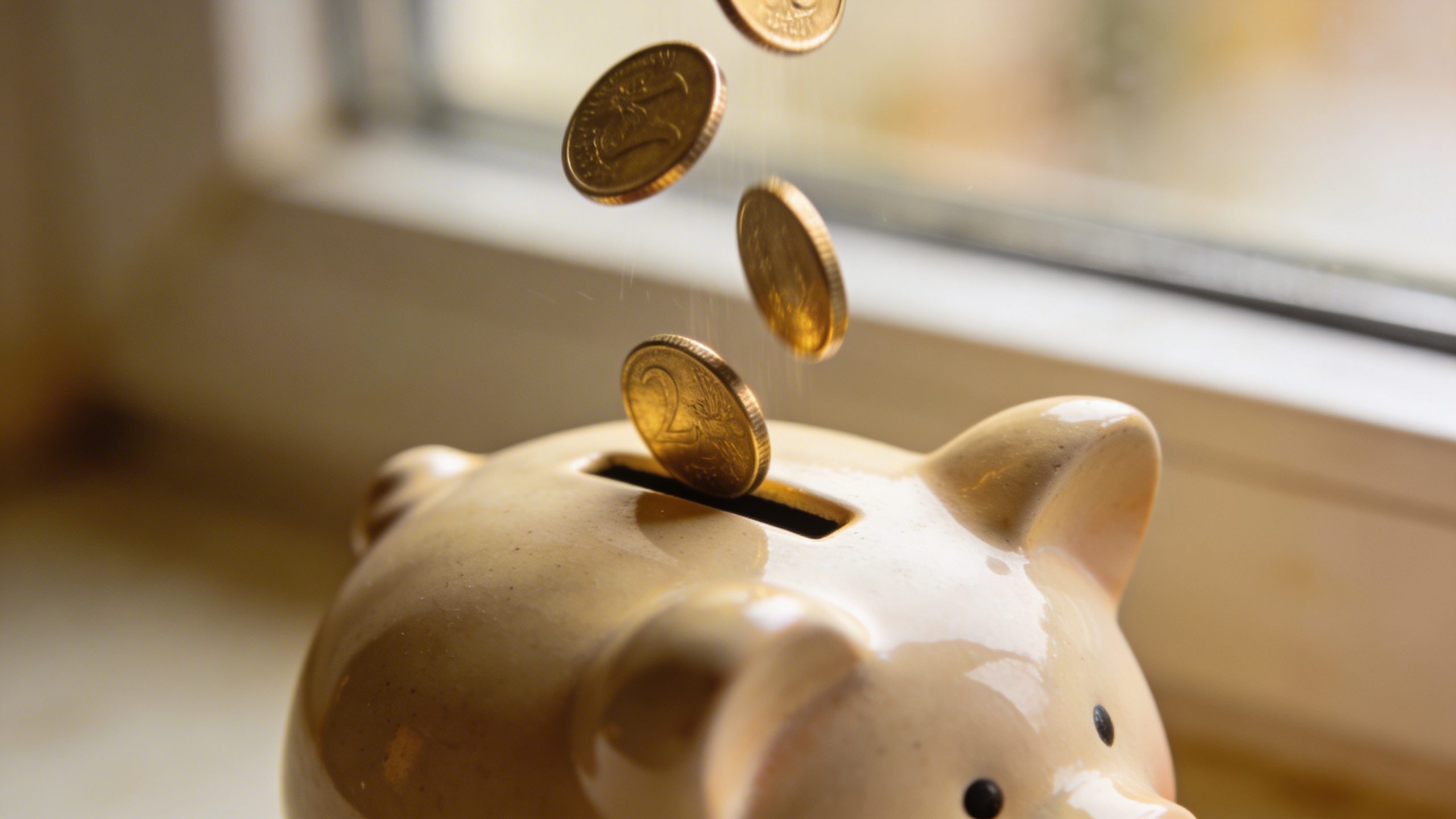 Closeup of a piggy bank being filled with coins, shallow depth of field