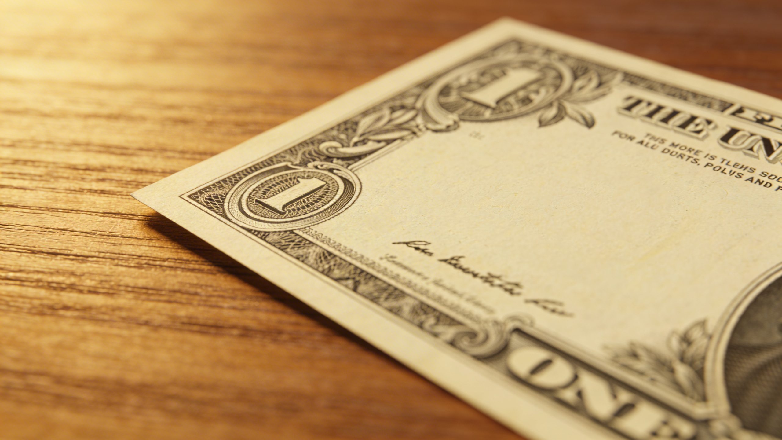 closeup of a single gratitude dollar bill on a wooden desk