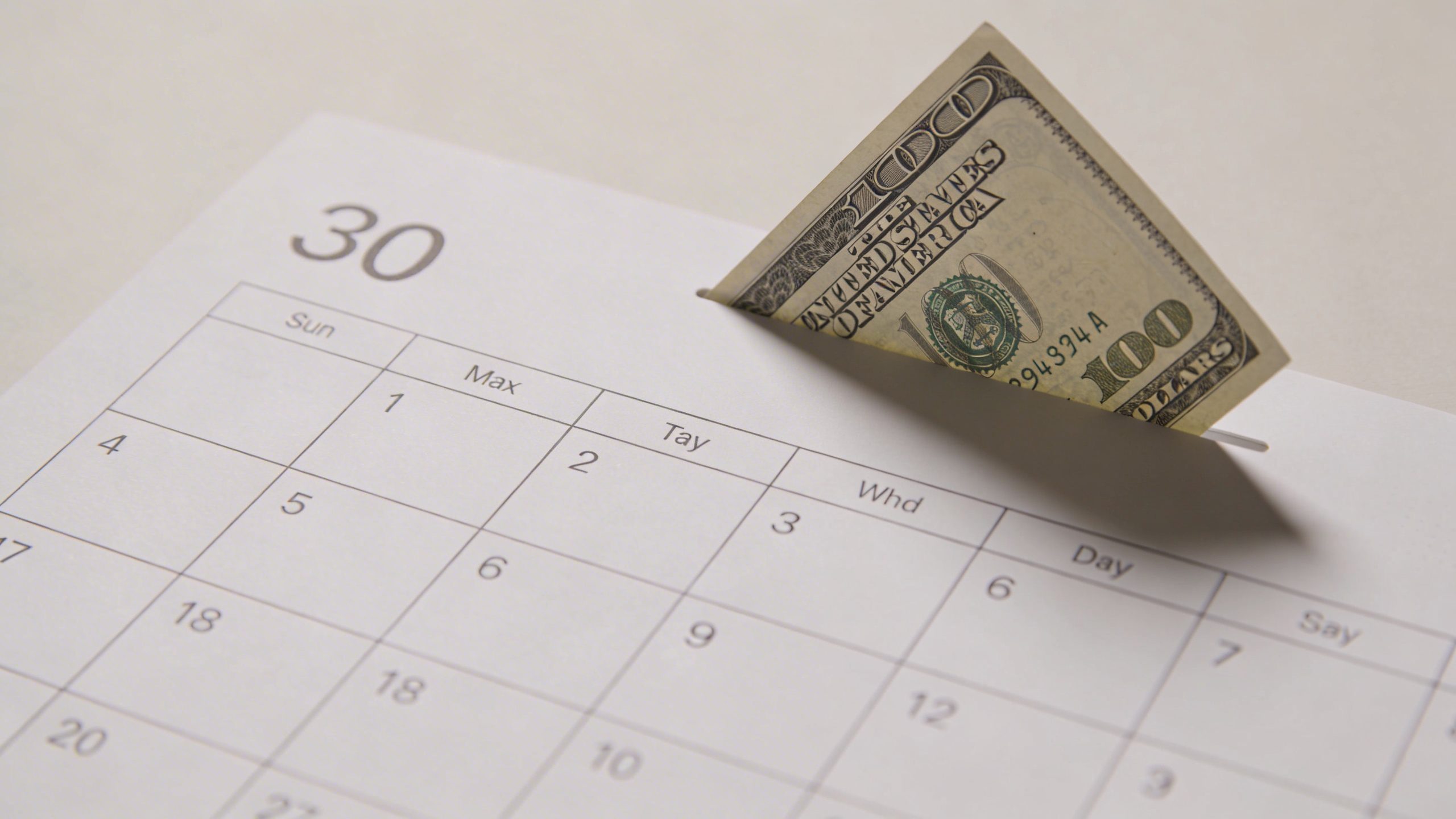 Closeup of a 30-day calendar page with a small saved-money note at corner