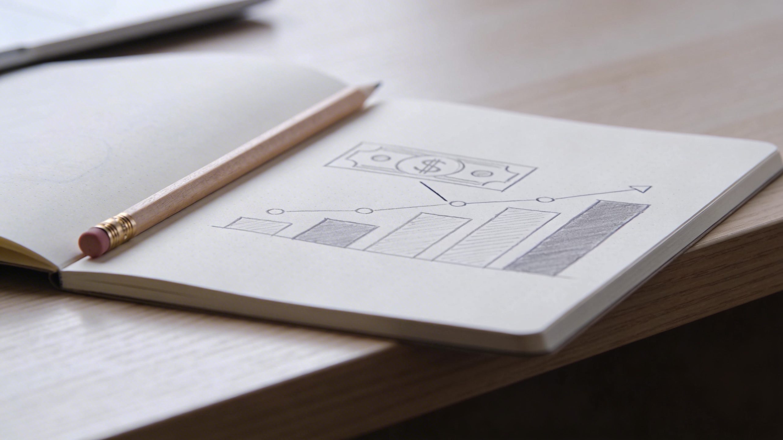 Closeup of a notebook and pencil on a clean desk, showing a money map