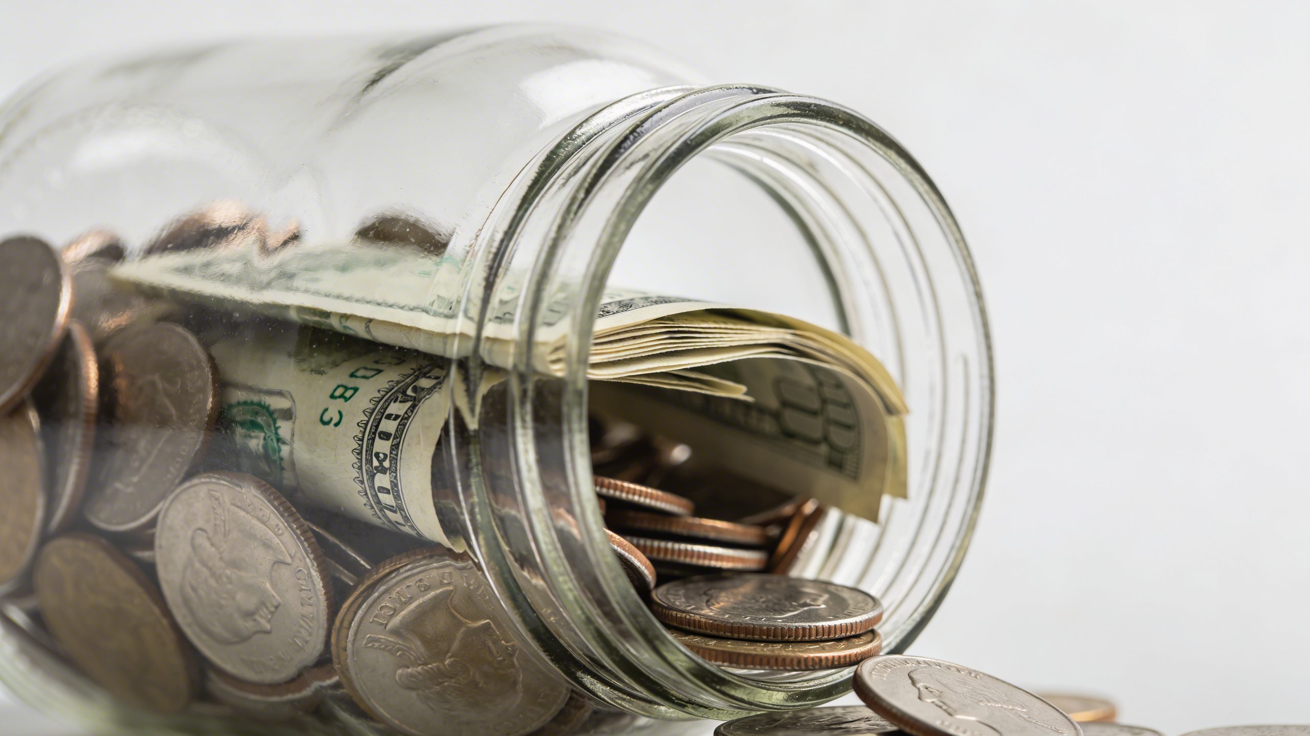 closeup of a transparent emergency fund jar with coins and bills