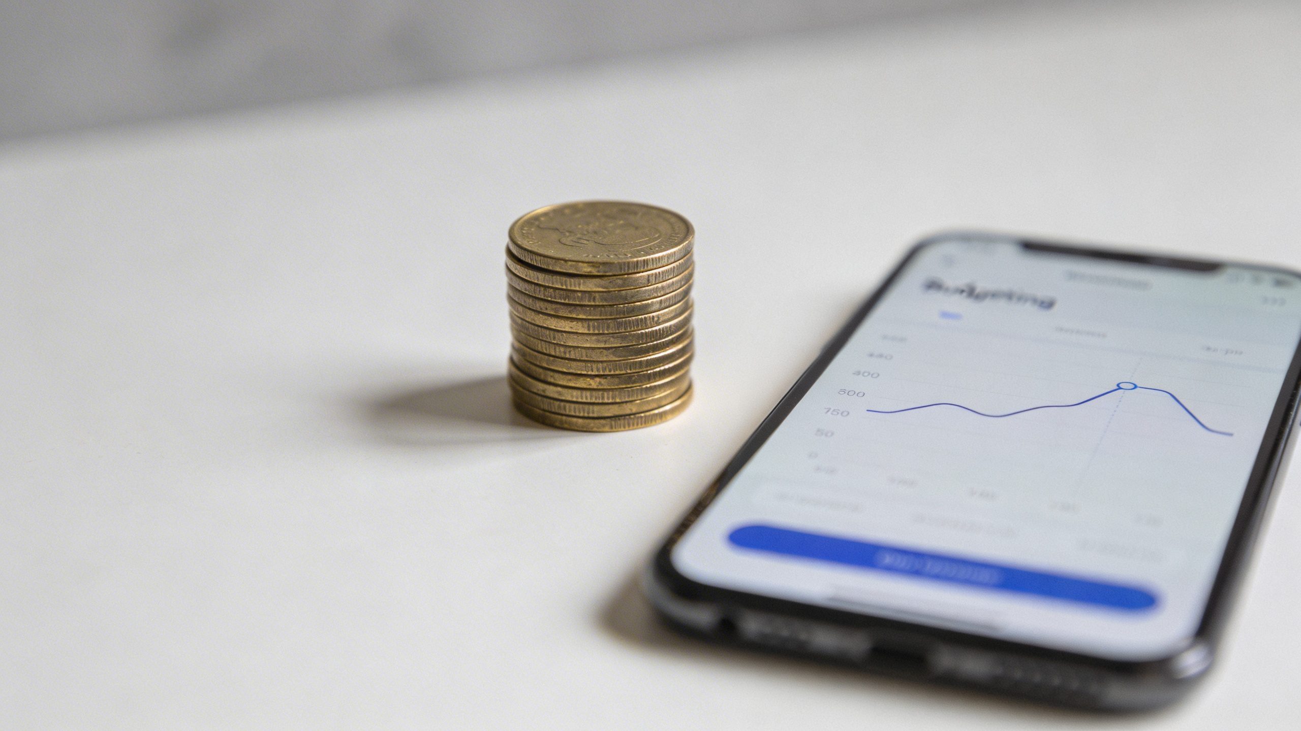 Focused shot of a single coin stack next to a minimalist budgeting app screen