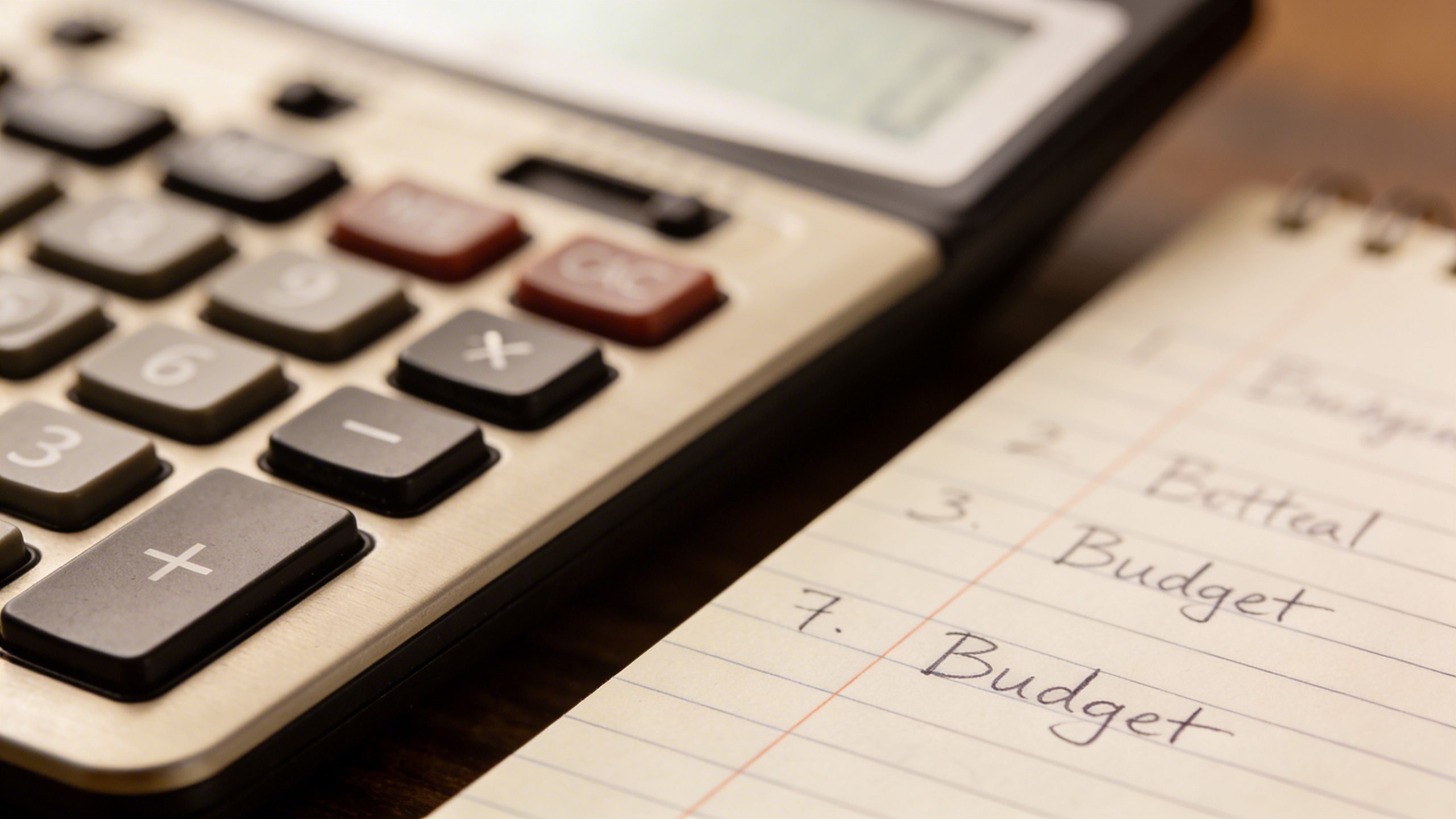 Closeup of a calculator and notebook with budget lines in focus