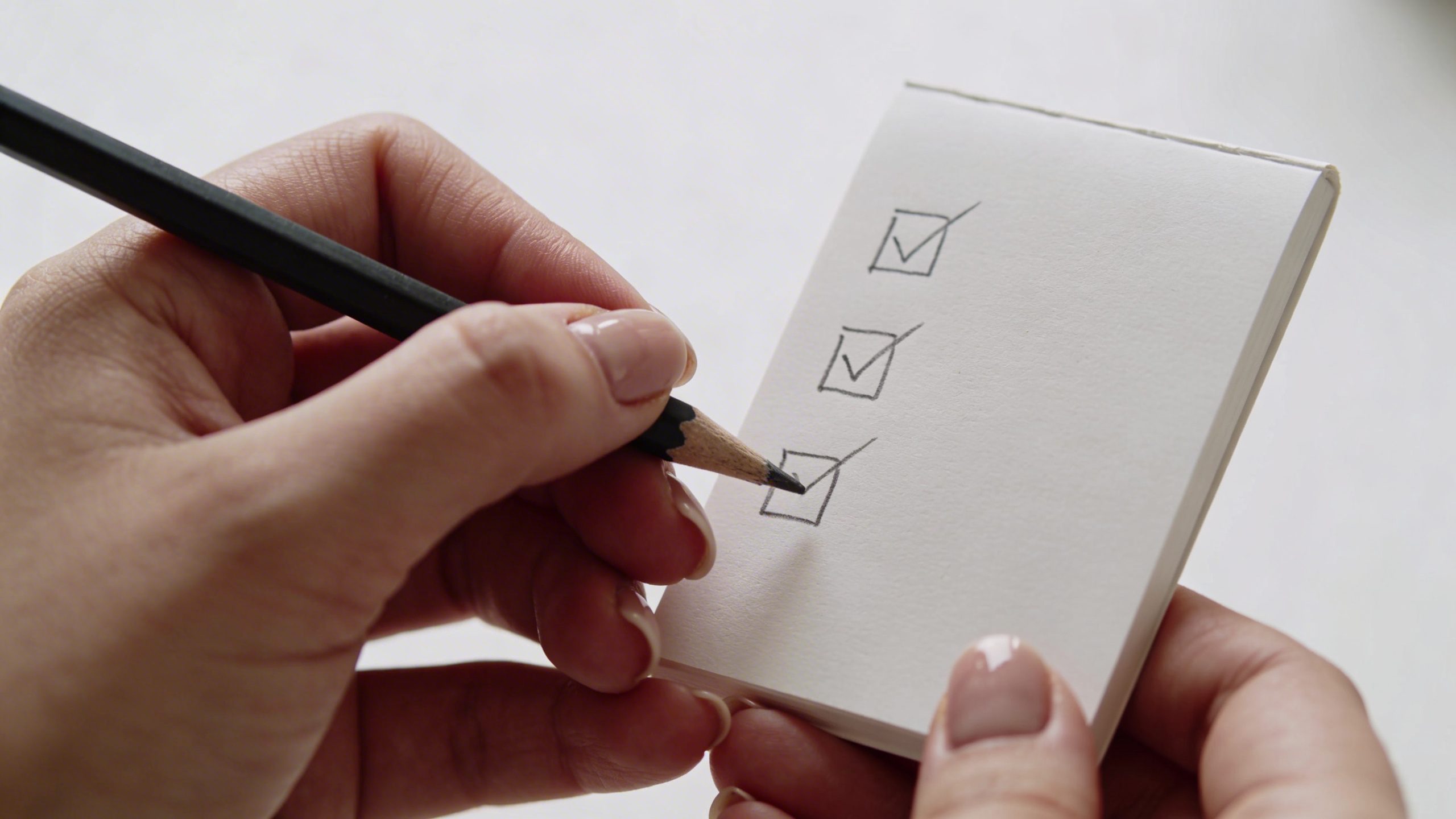 Close-up of a person counting a 3-item shopping list on a white background