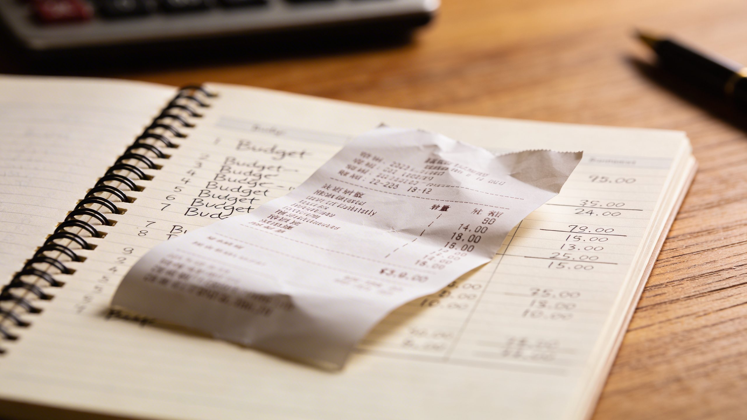 Closeup receipt with budget-spread notebook on desk