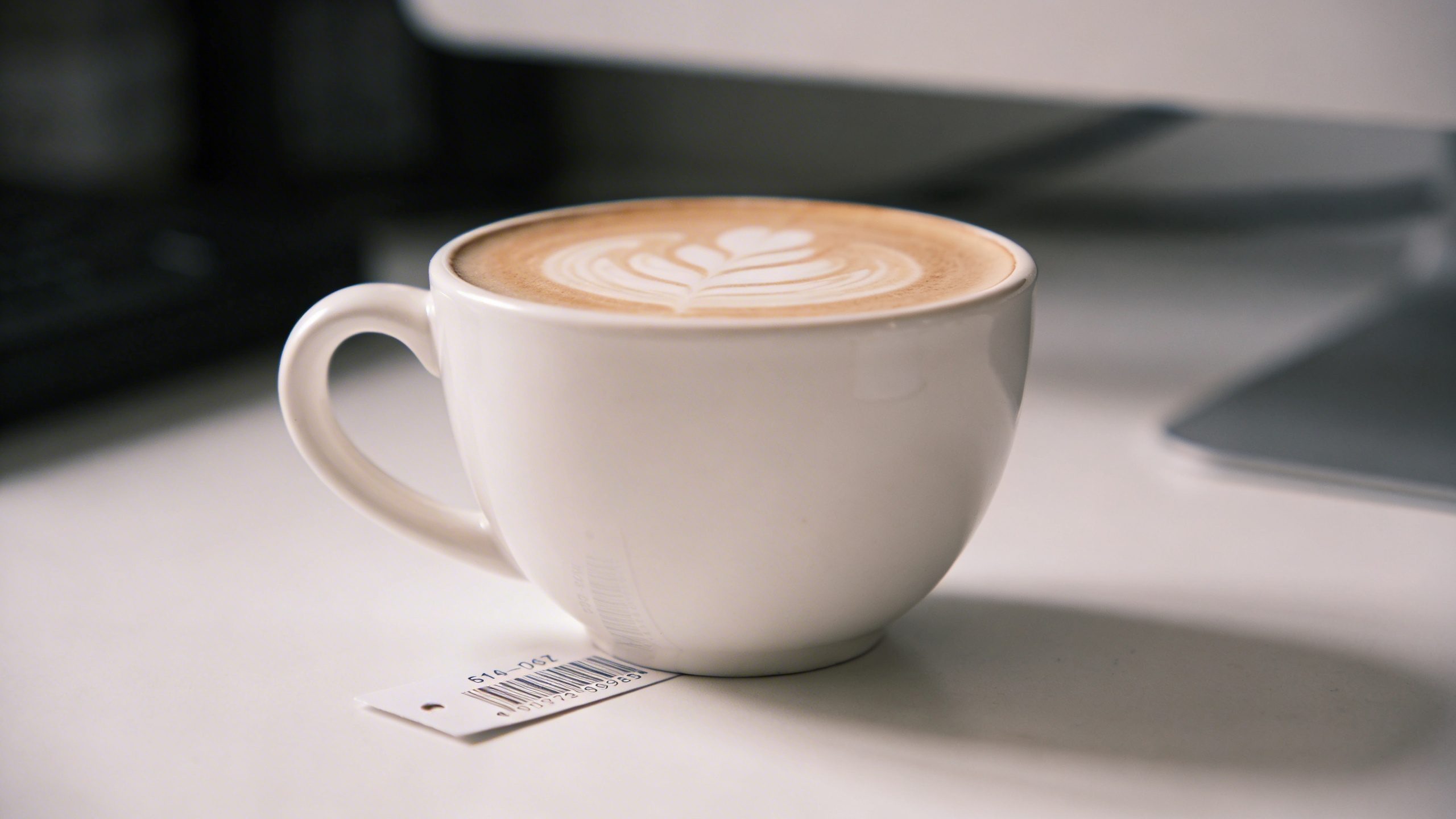 Close-up of a single latte cup with a visible price tag slip on a clean desk
