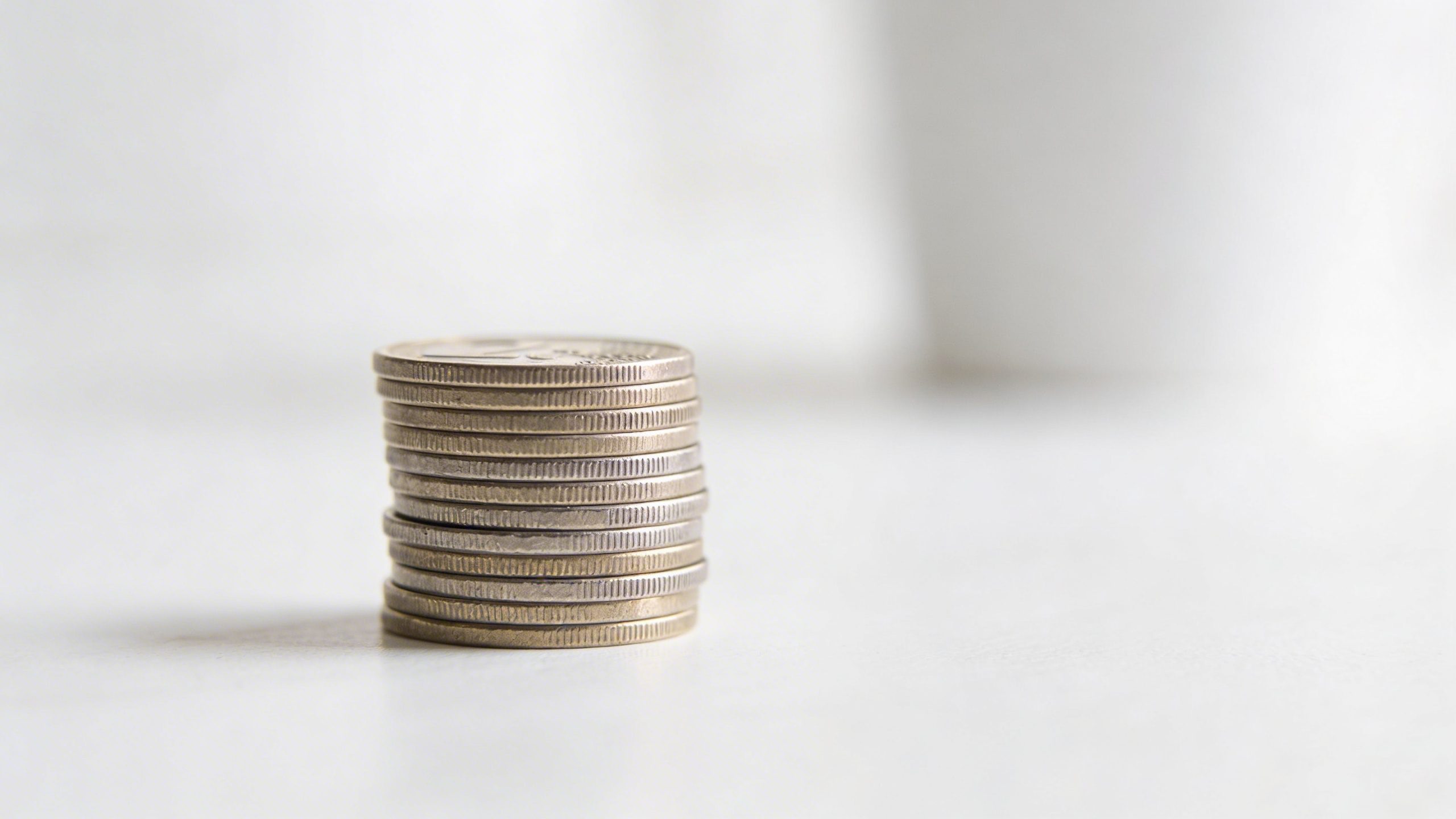 closeup of a lone tidy coin stack on a minimalist white surface