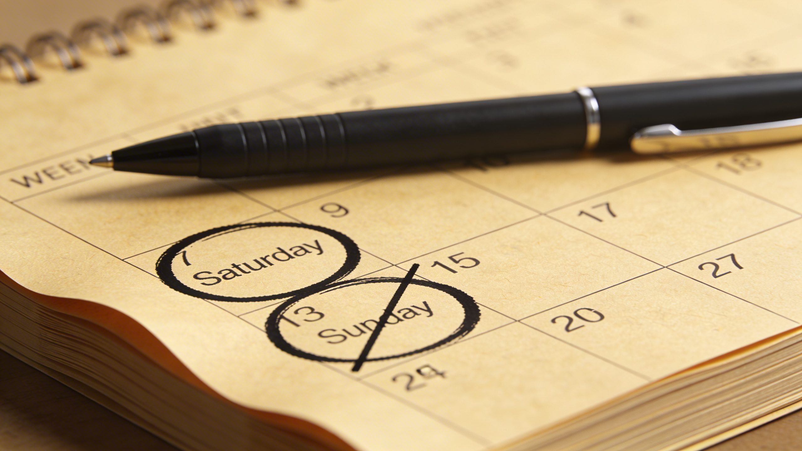 Closeup of a desk calendar marking weekend freelancer schedule with a pen