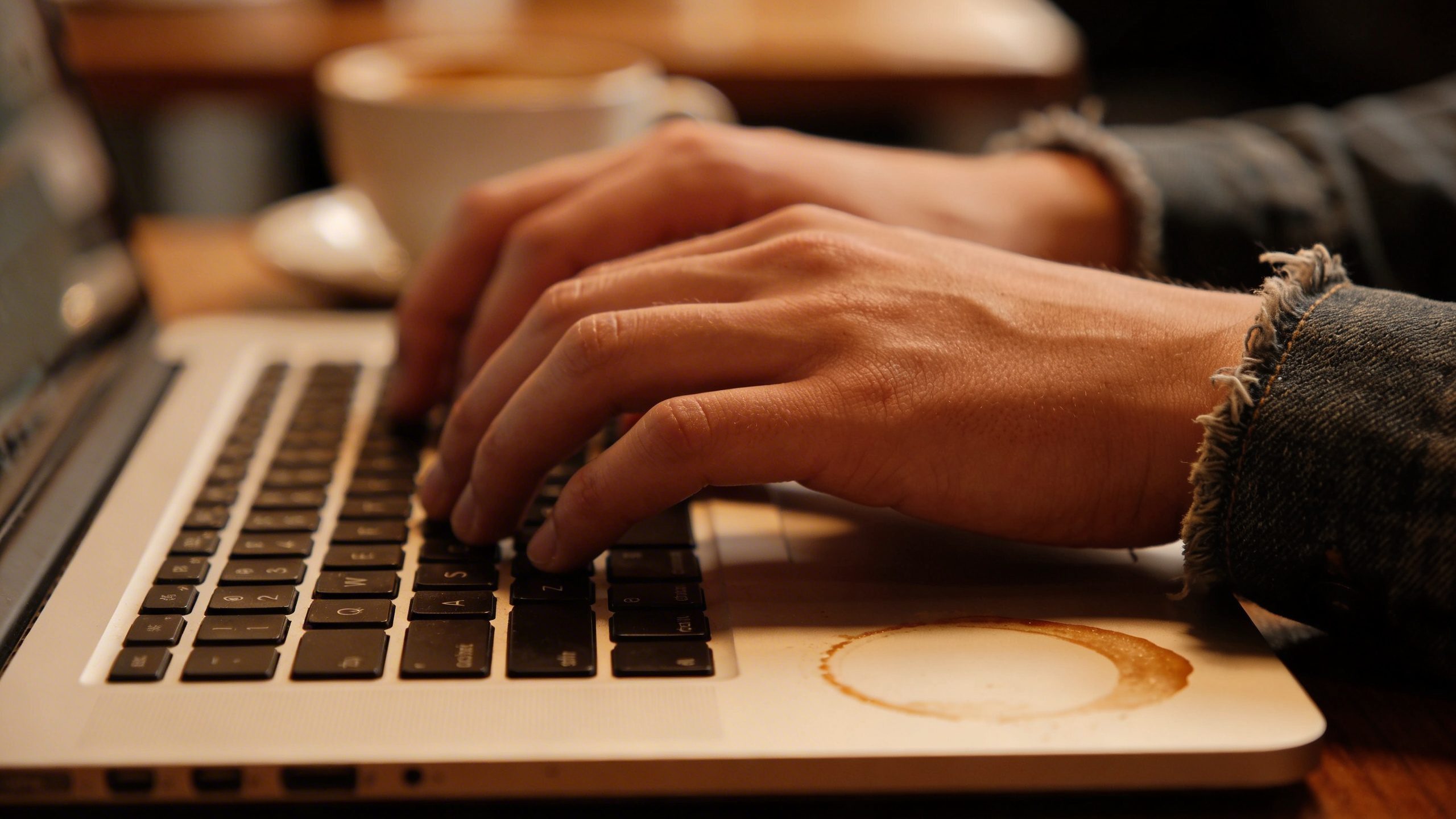 Close-up of a freelancer typing on a laptop in a coffee shop