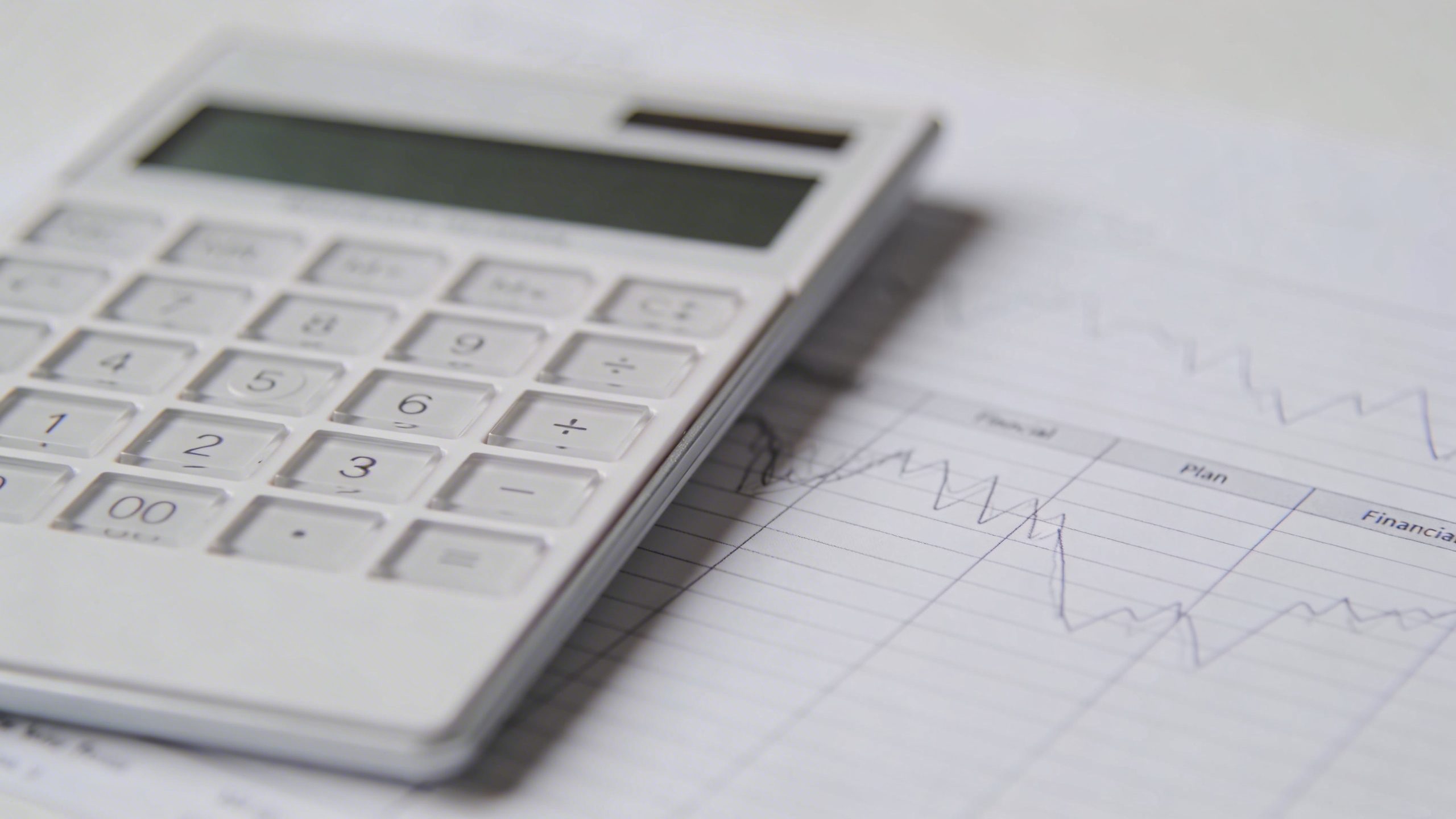 Closeup of a minimalist calculator beside a financial plan page