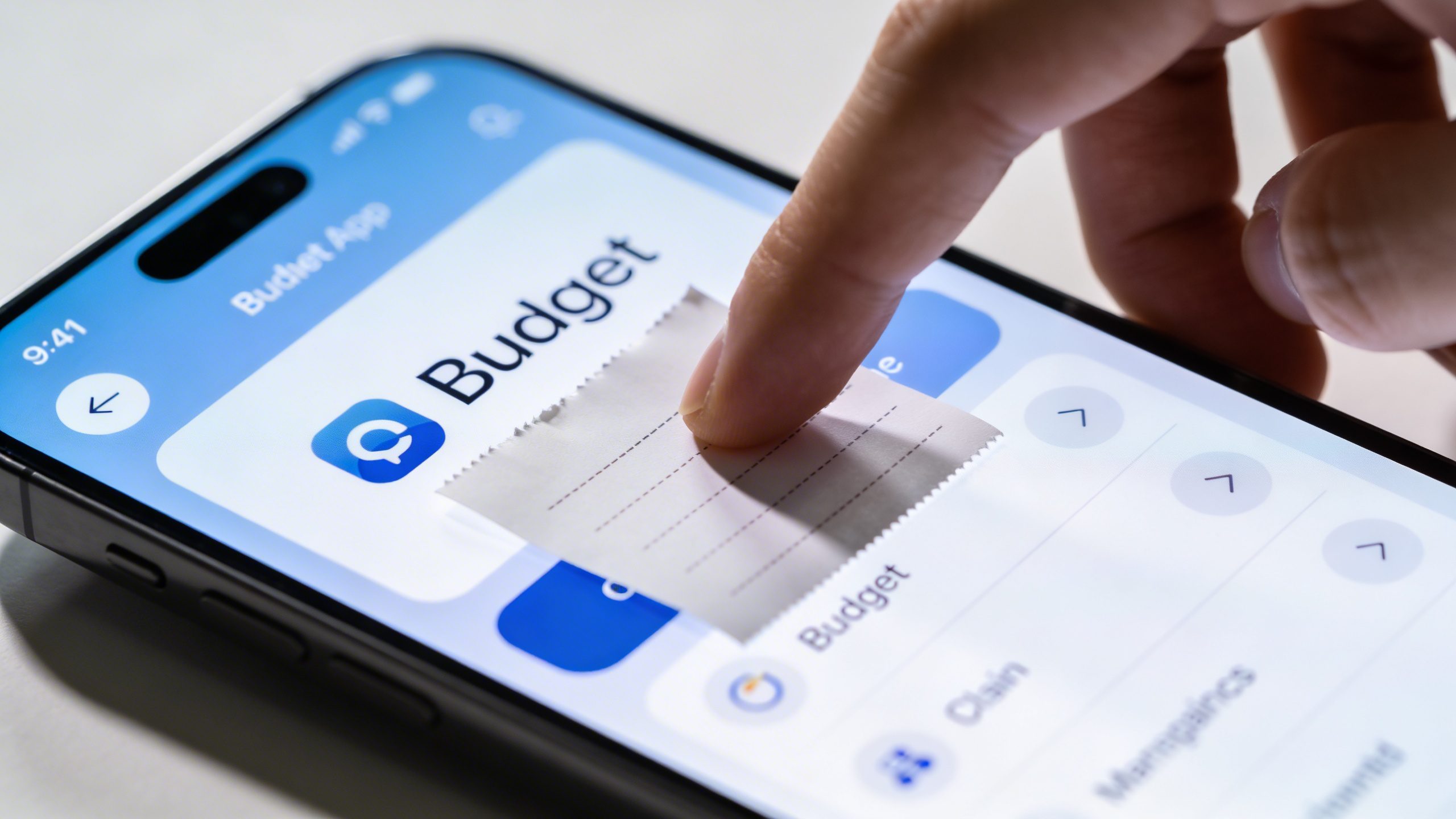 closeup of a hand entering a small receipt into a clean budget app on a smartphone