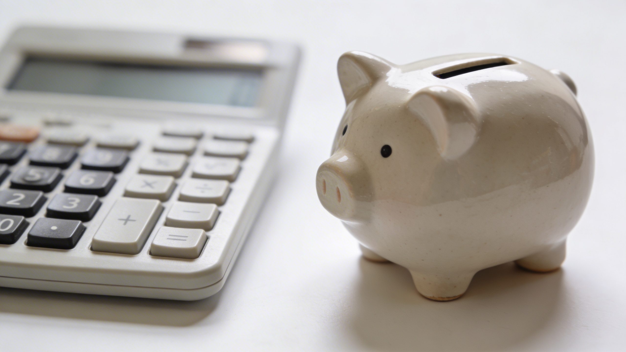 Focused shot of a single piggy bank beside a calculator on a clean desk