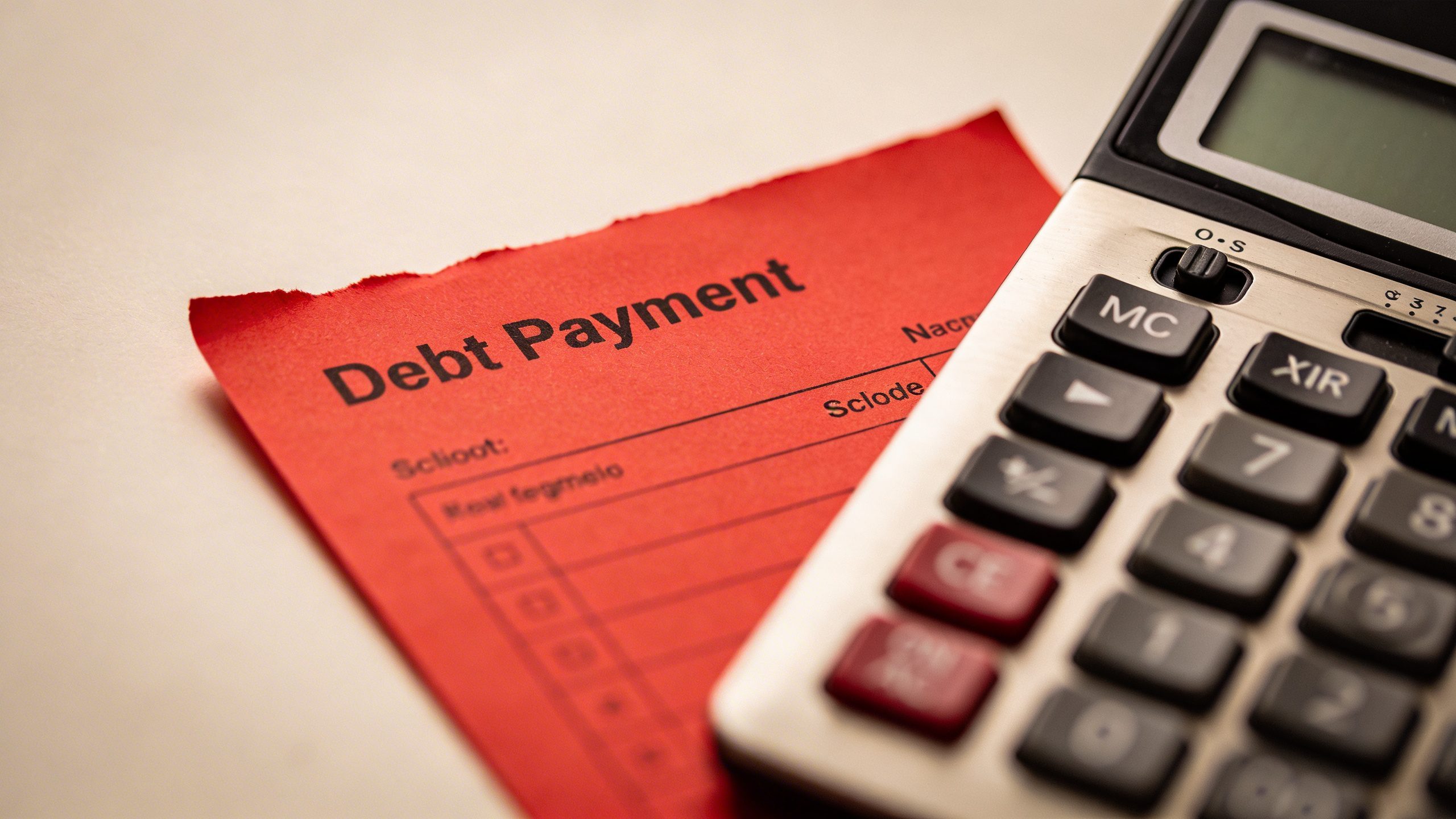Closeup of a single debt payoff calculator beside a red debt payment slip