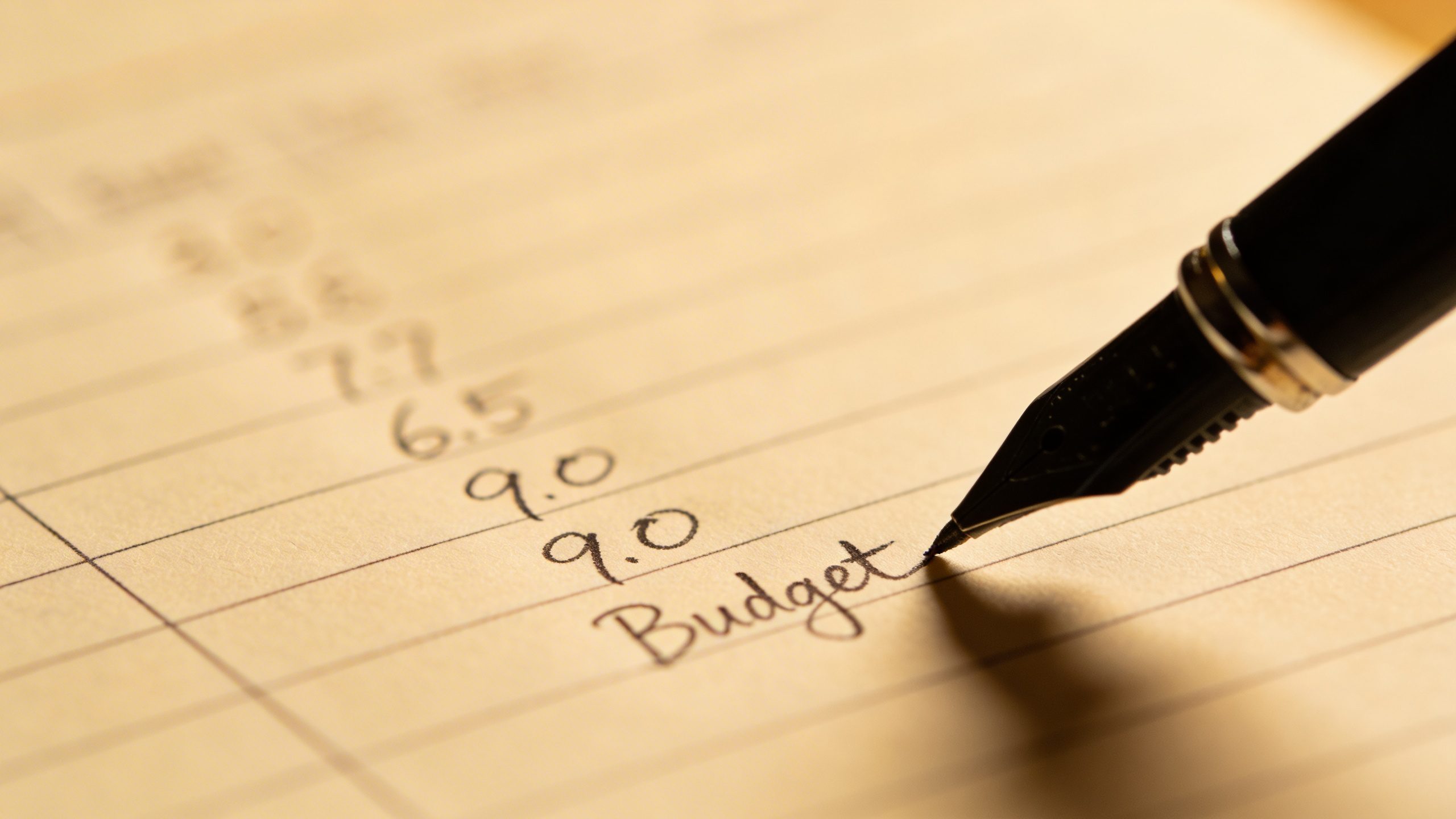 Closeup of a single pen writing budget on paper with line items