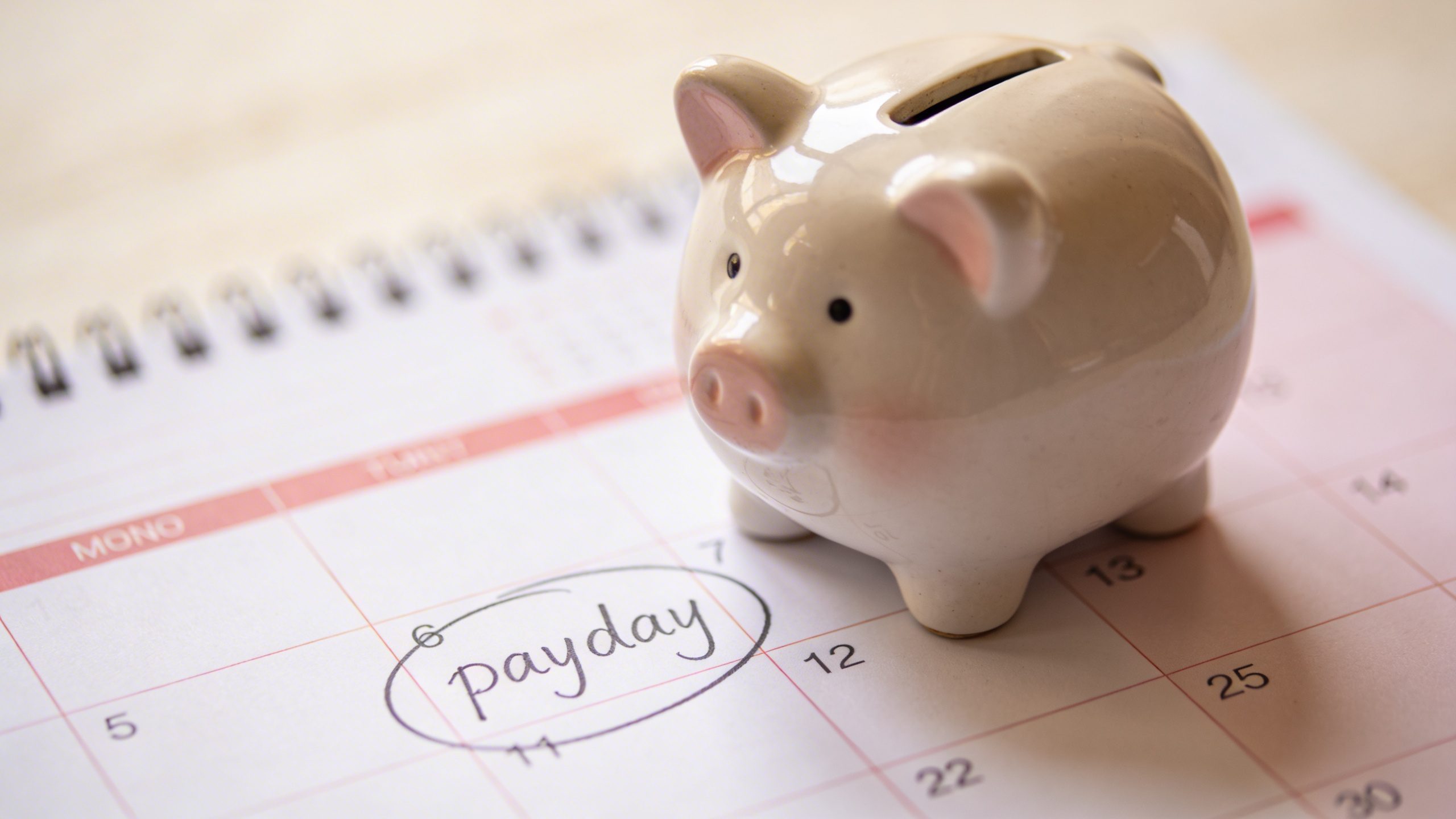 Focused shot of a calendar page marking a payday with a piggy bank nearby